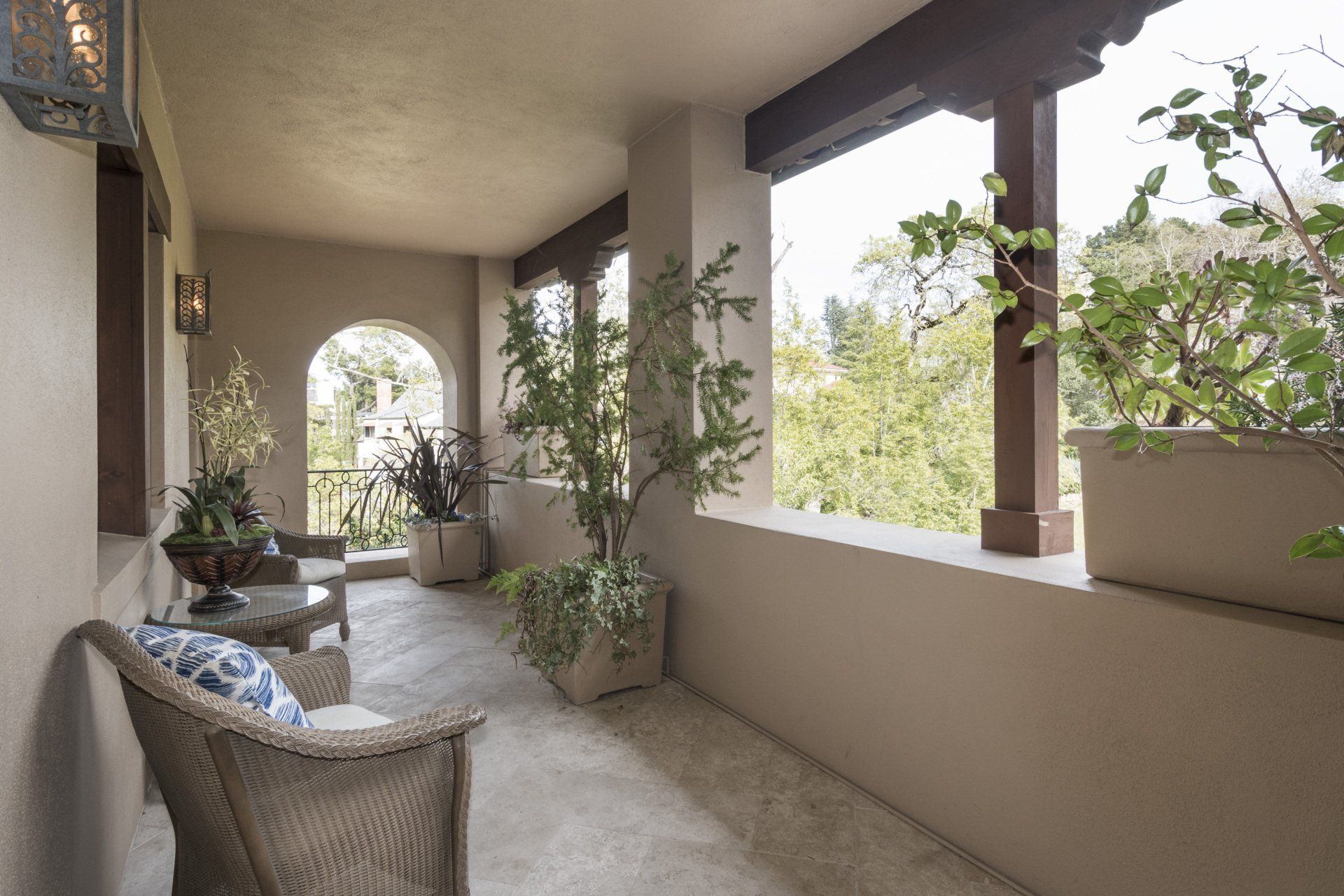 A large porch with wicker furniture and plants