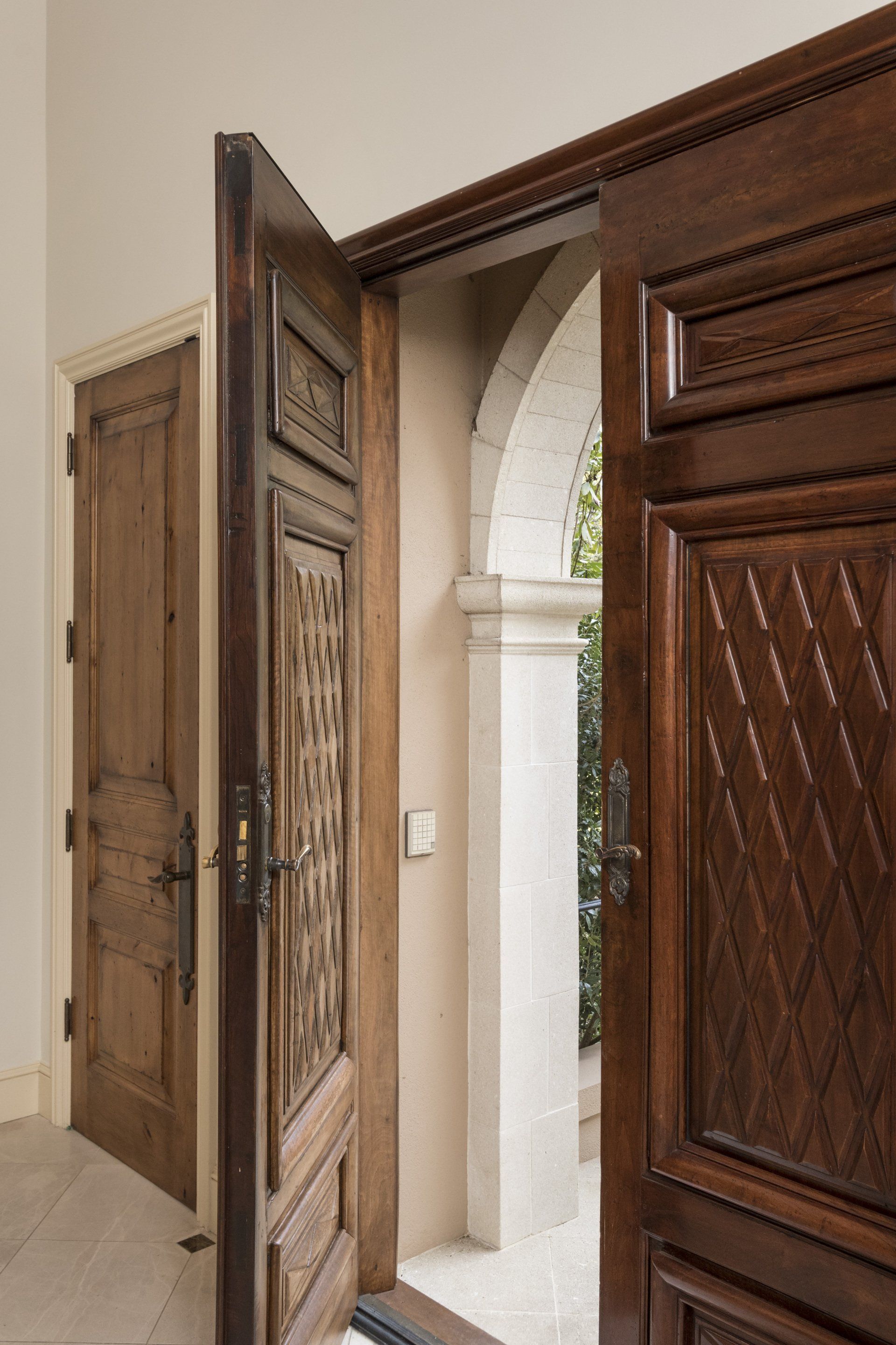 A wooden door is open to a hallway with a stone archway.