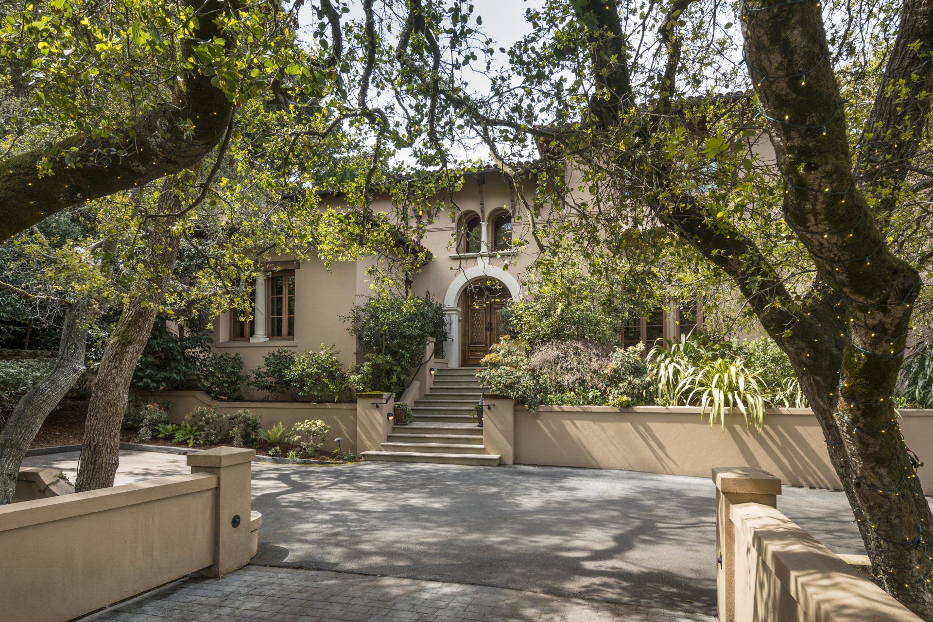 A large house with a driveway and trees in front of it.