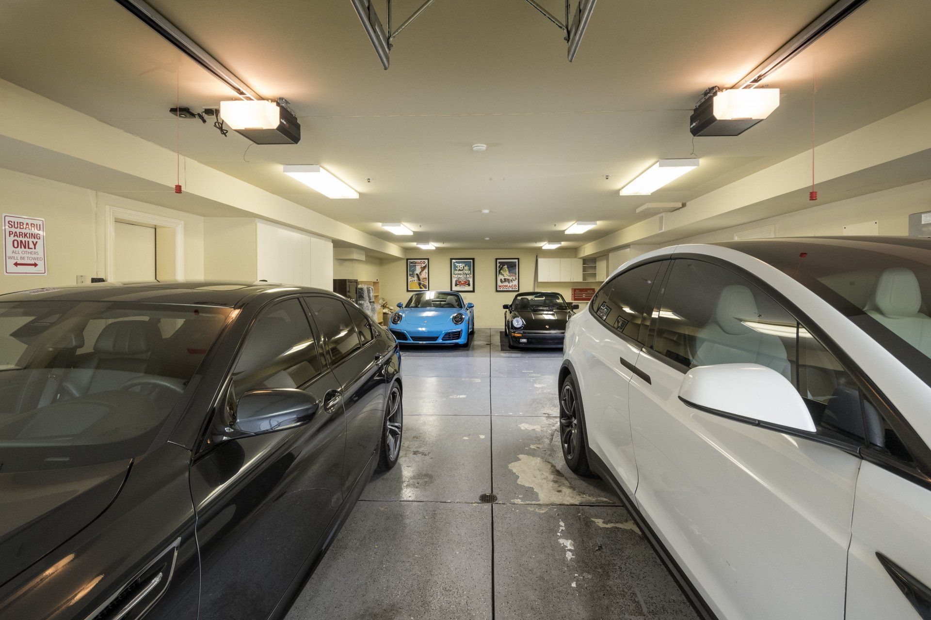 A white car is parked in a garage next to a black car