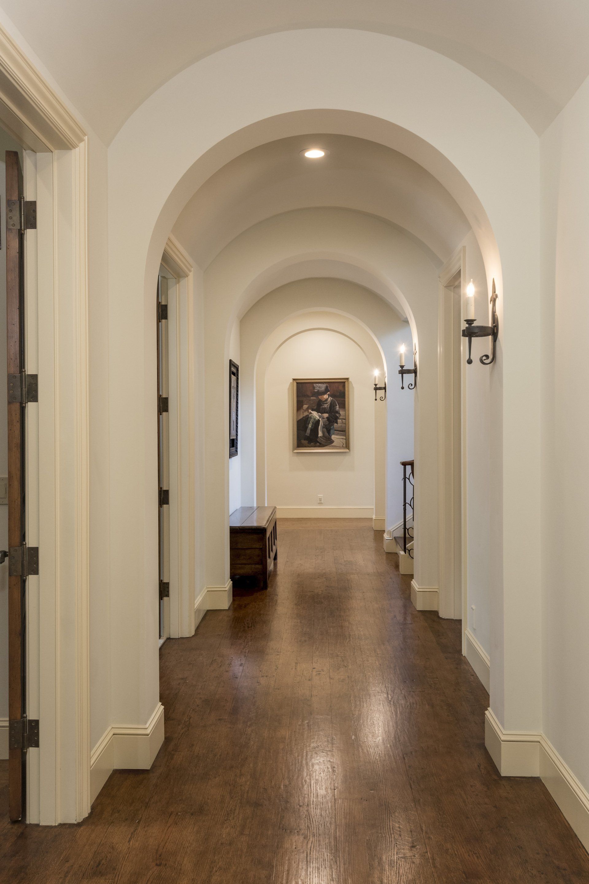 A long hallway with arches and a picture on the wall
