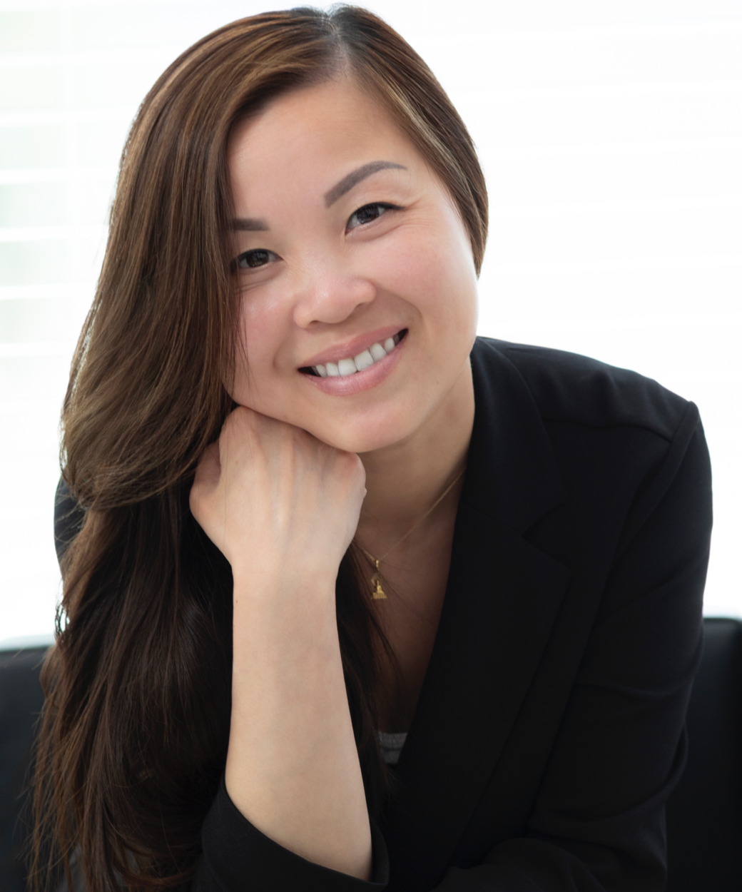 A woman in a suit is smiling in a black and white photo.