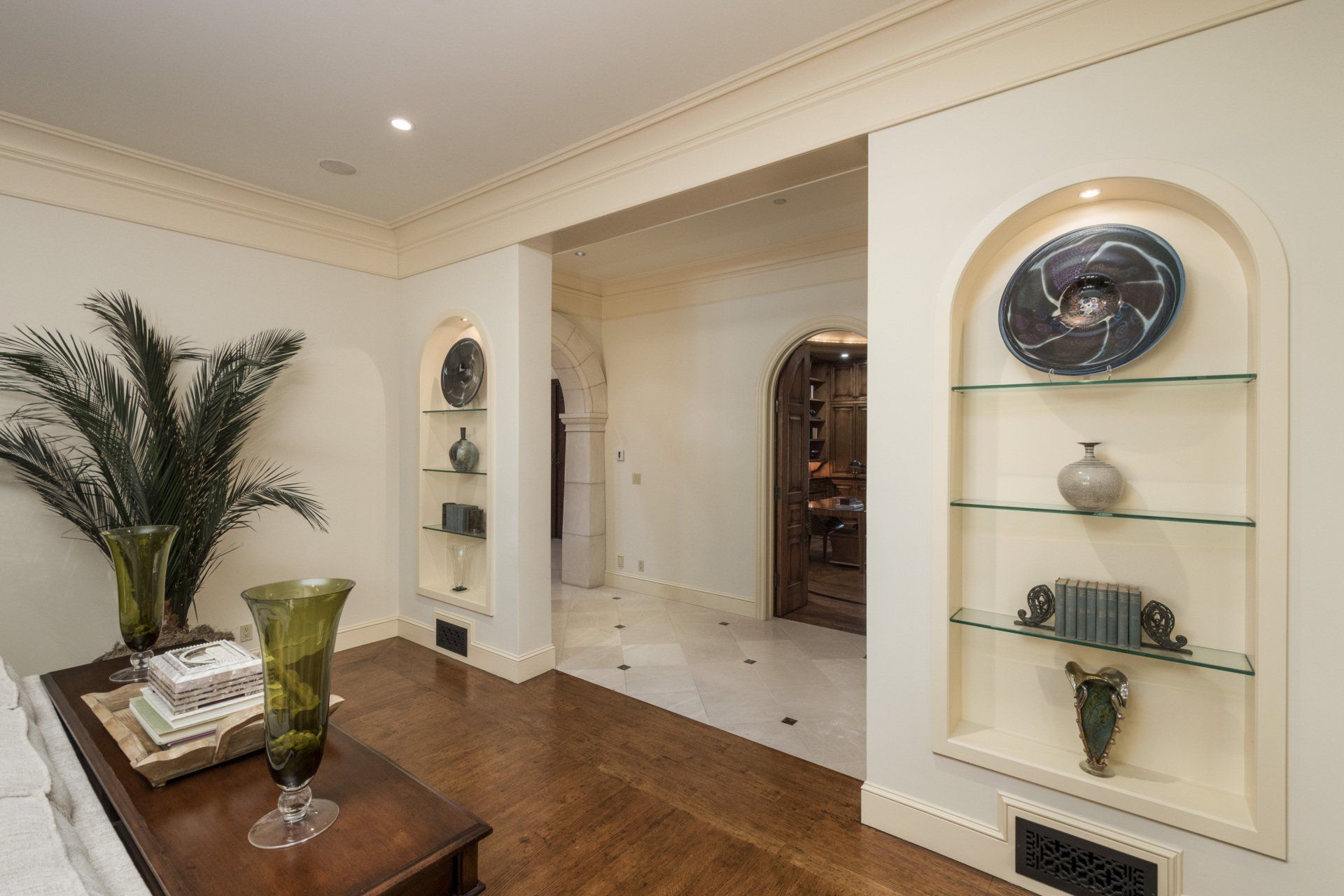 A room with a table and shelves with vases on them