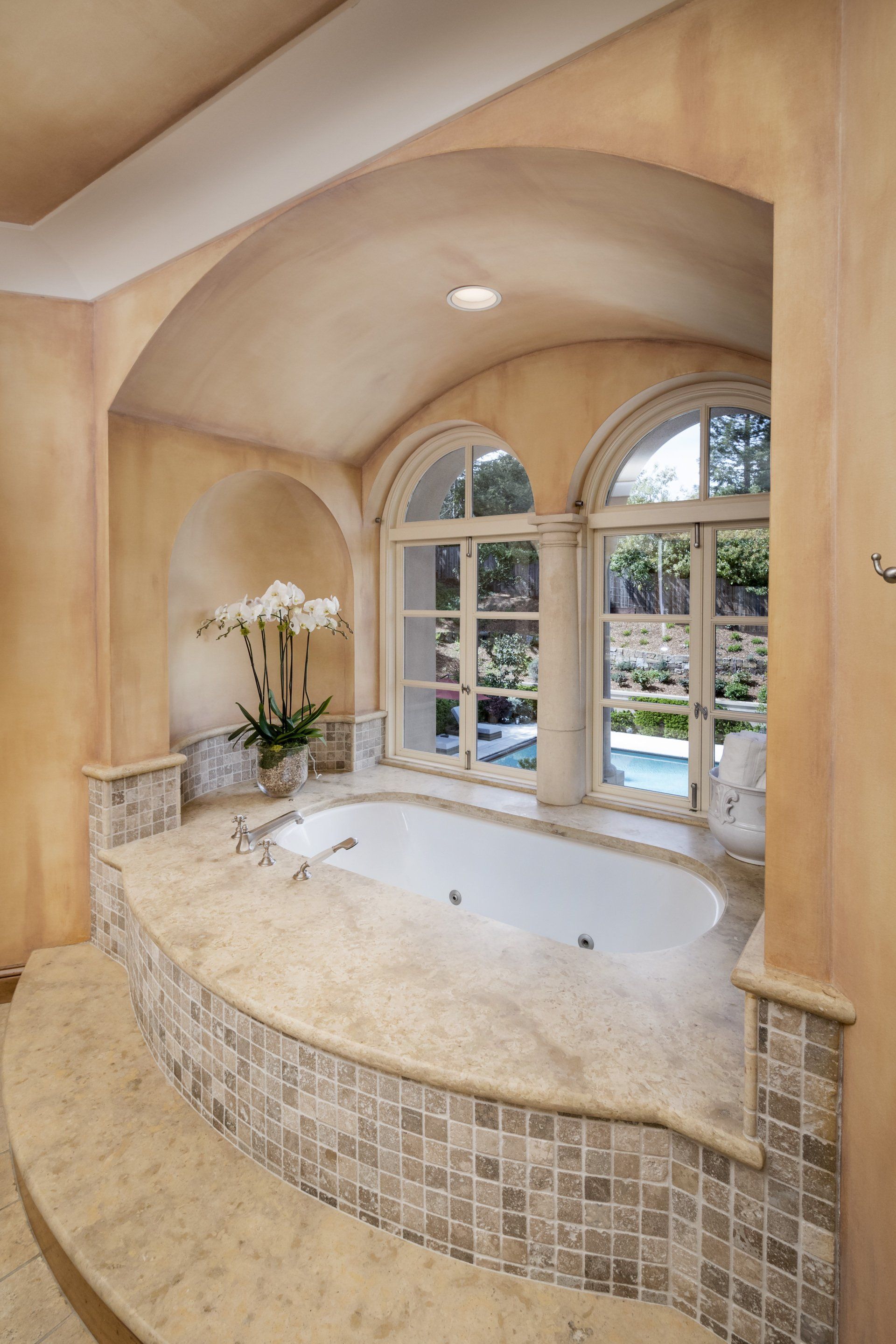 A bathtub in a bathroom with arched windows