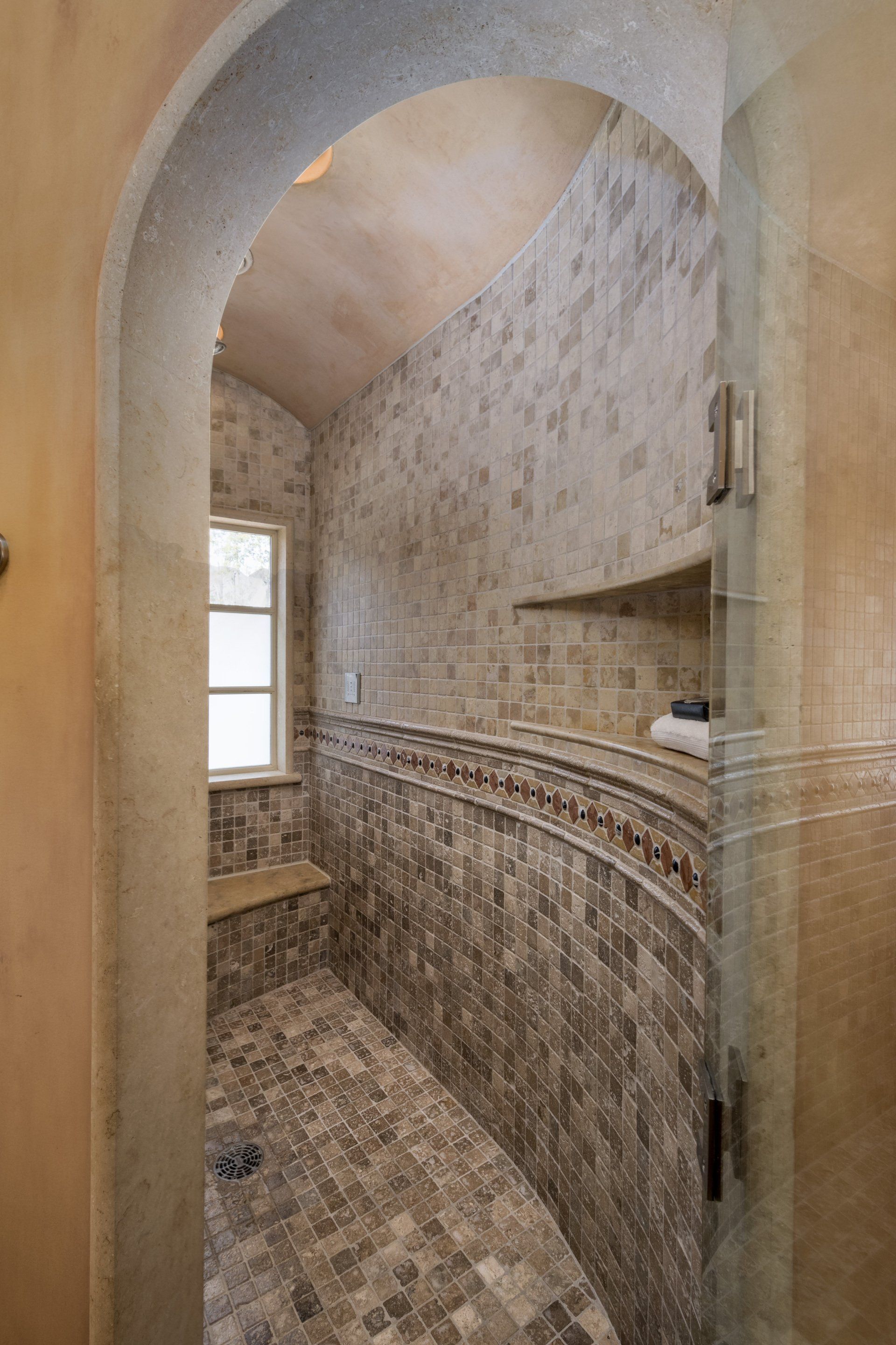 A bathroom with a walk in shower and a window.