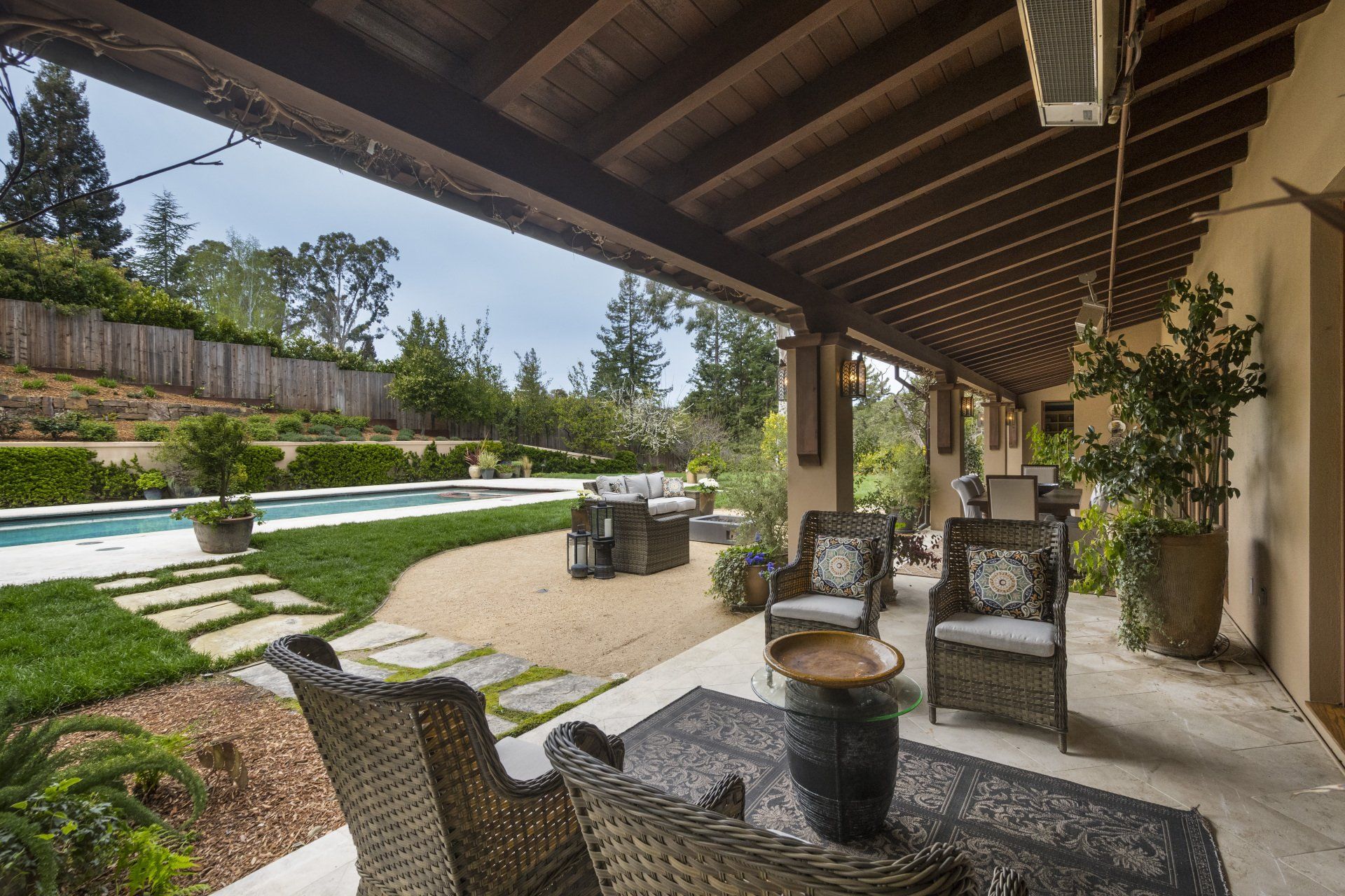 A patio with chairs and a table with a pool in the background