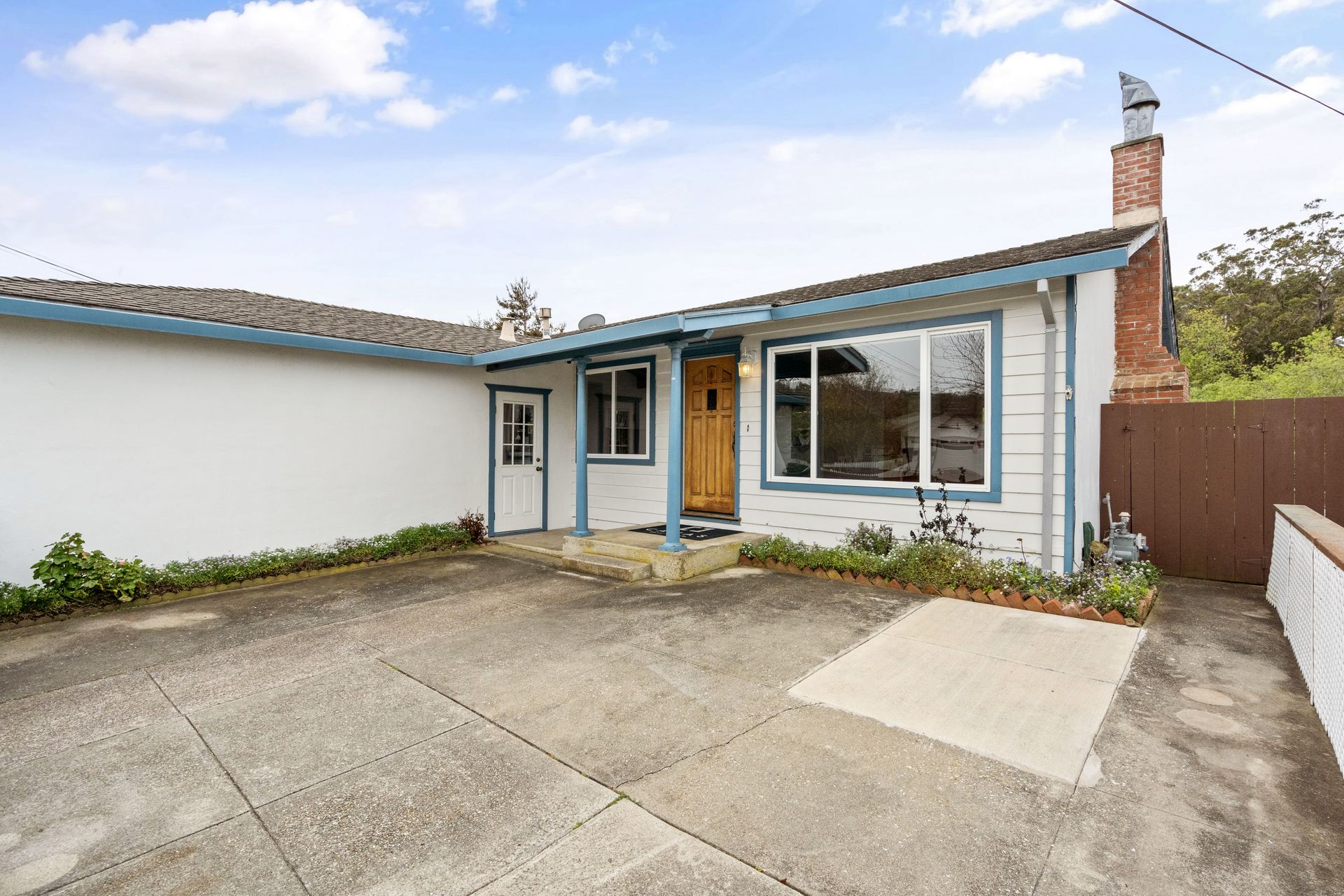 A white house with blue trim and a brick chimney.