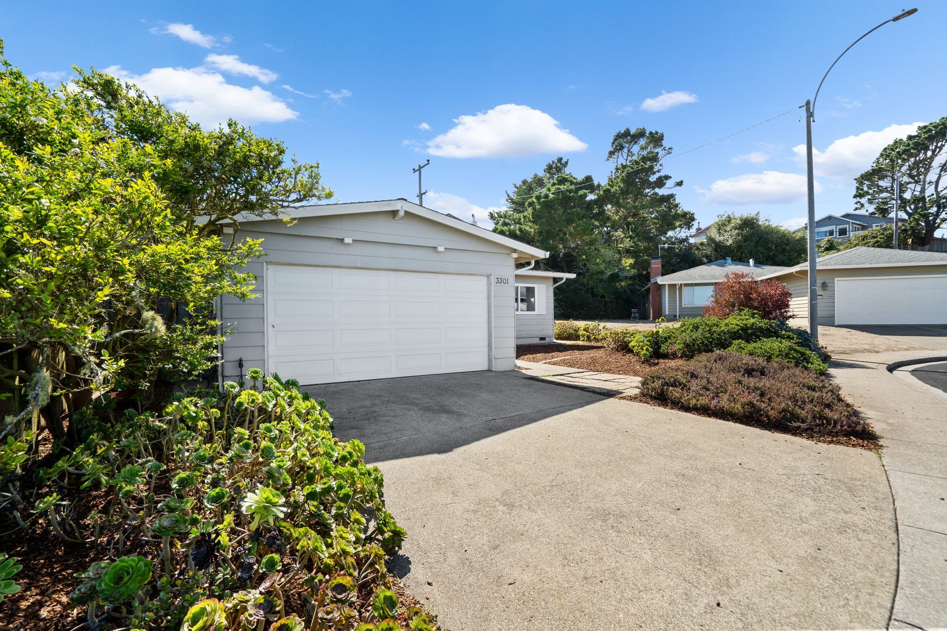 A white garage with a driveway in front of it.