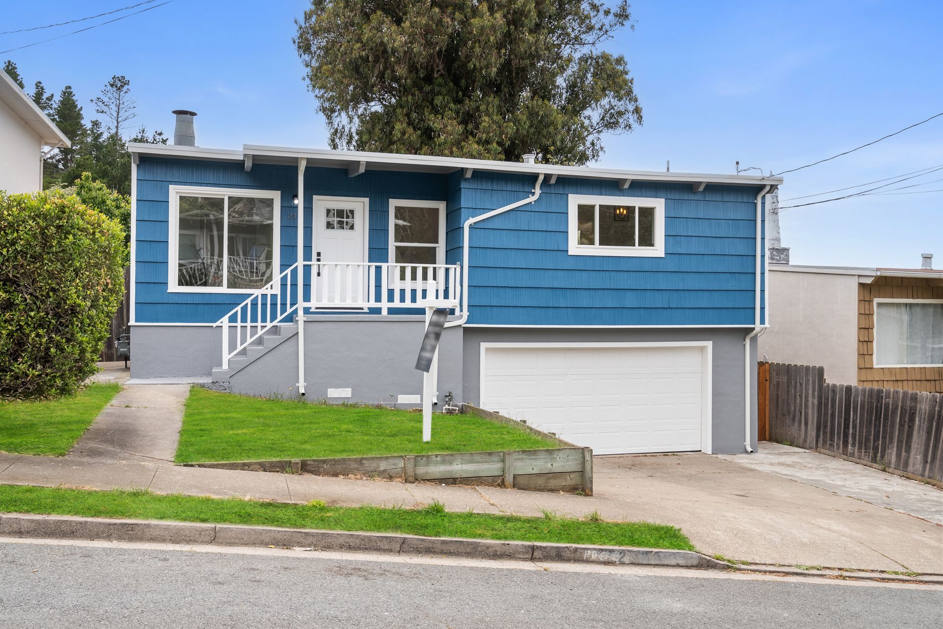 A blue and gray house with a garage and stairs.