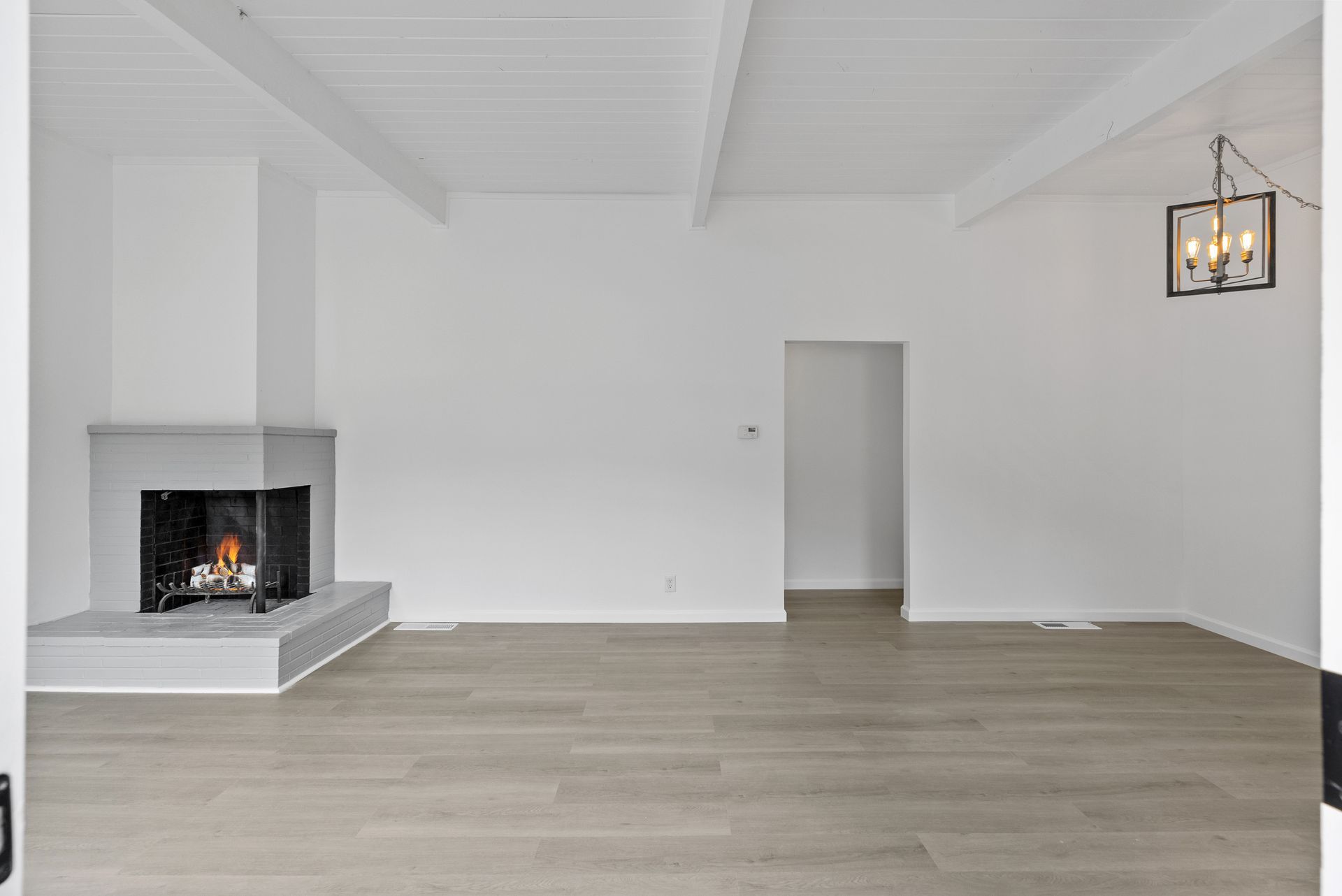 An empty living room with a fireplace and a light.