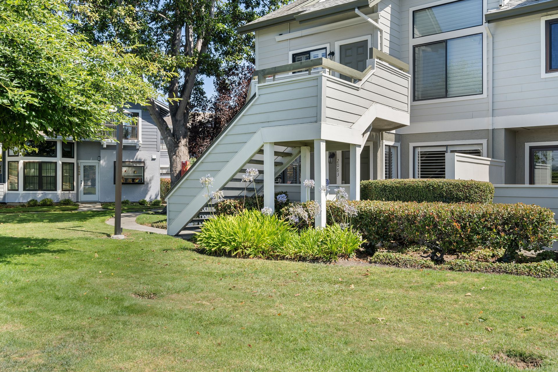 A large white house with stairs leading up to the second floor.