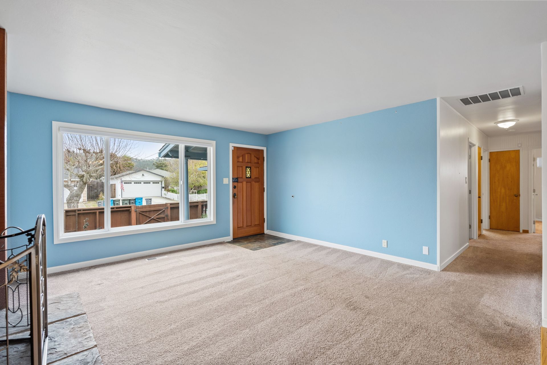 An empty living room with blue walls and a large window