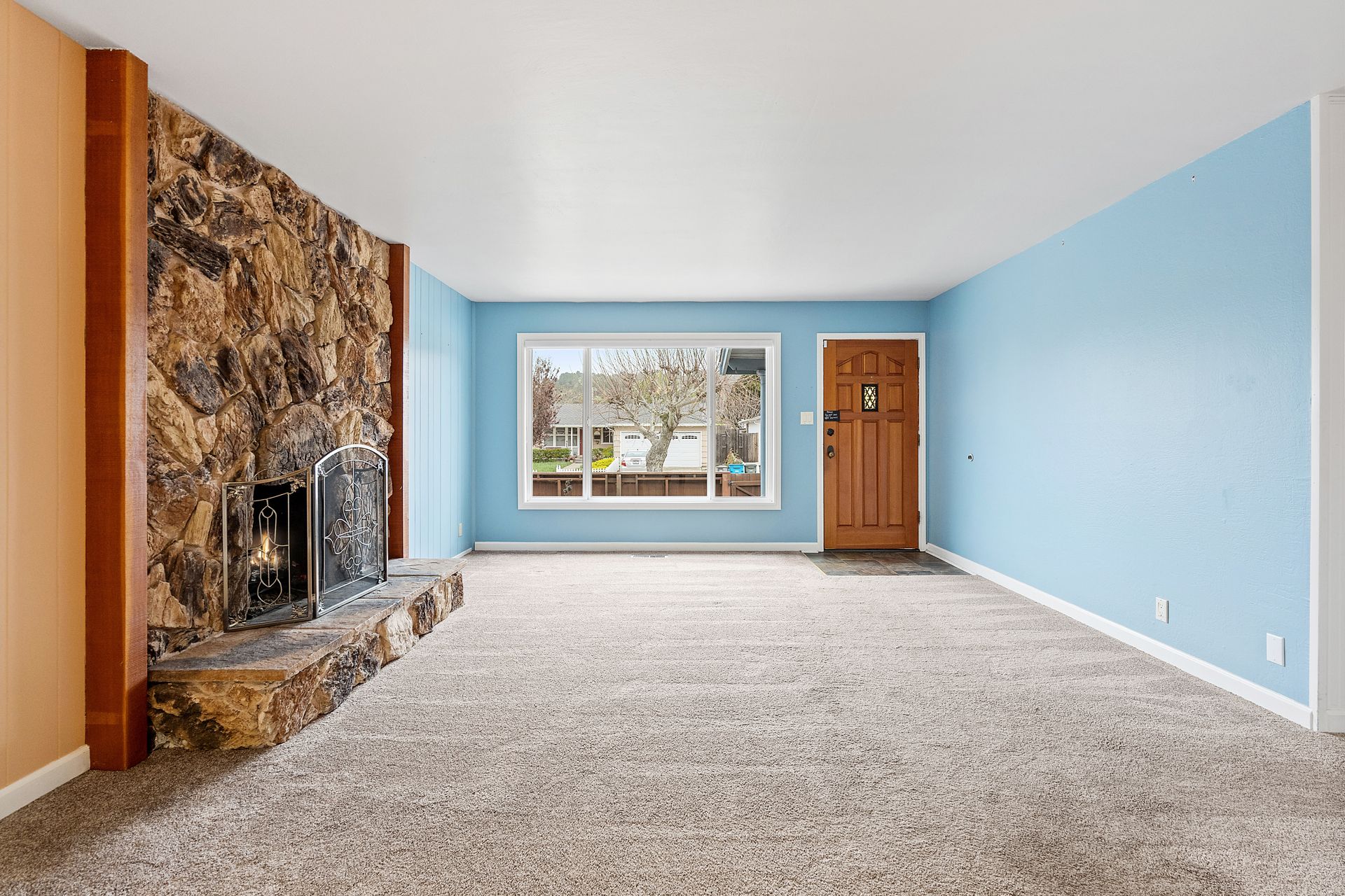 An empty living room with blue walls and a fireplace.