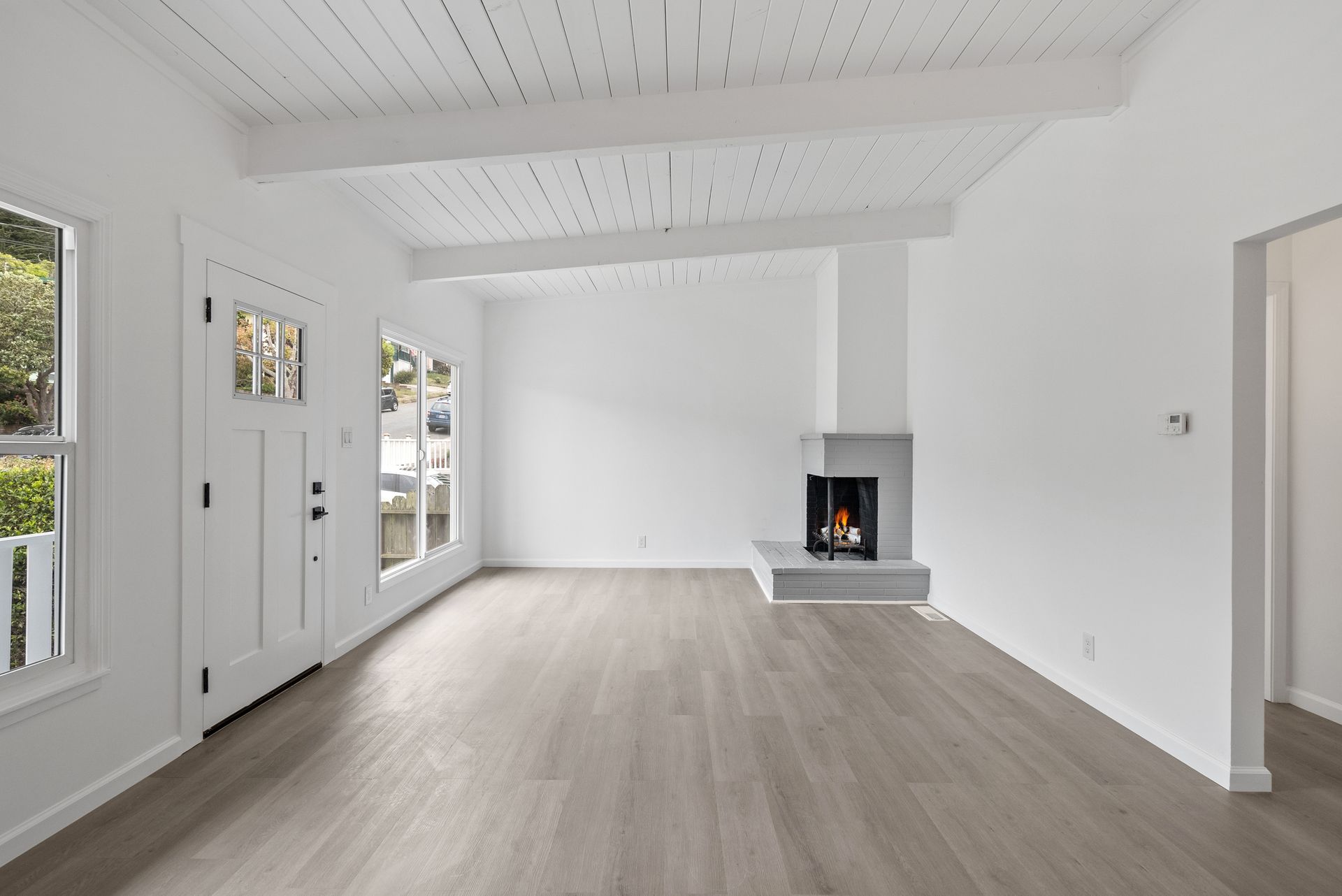 An empty living room with hardwood floors and a fireplace.