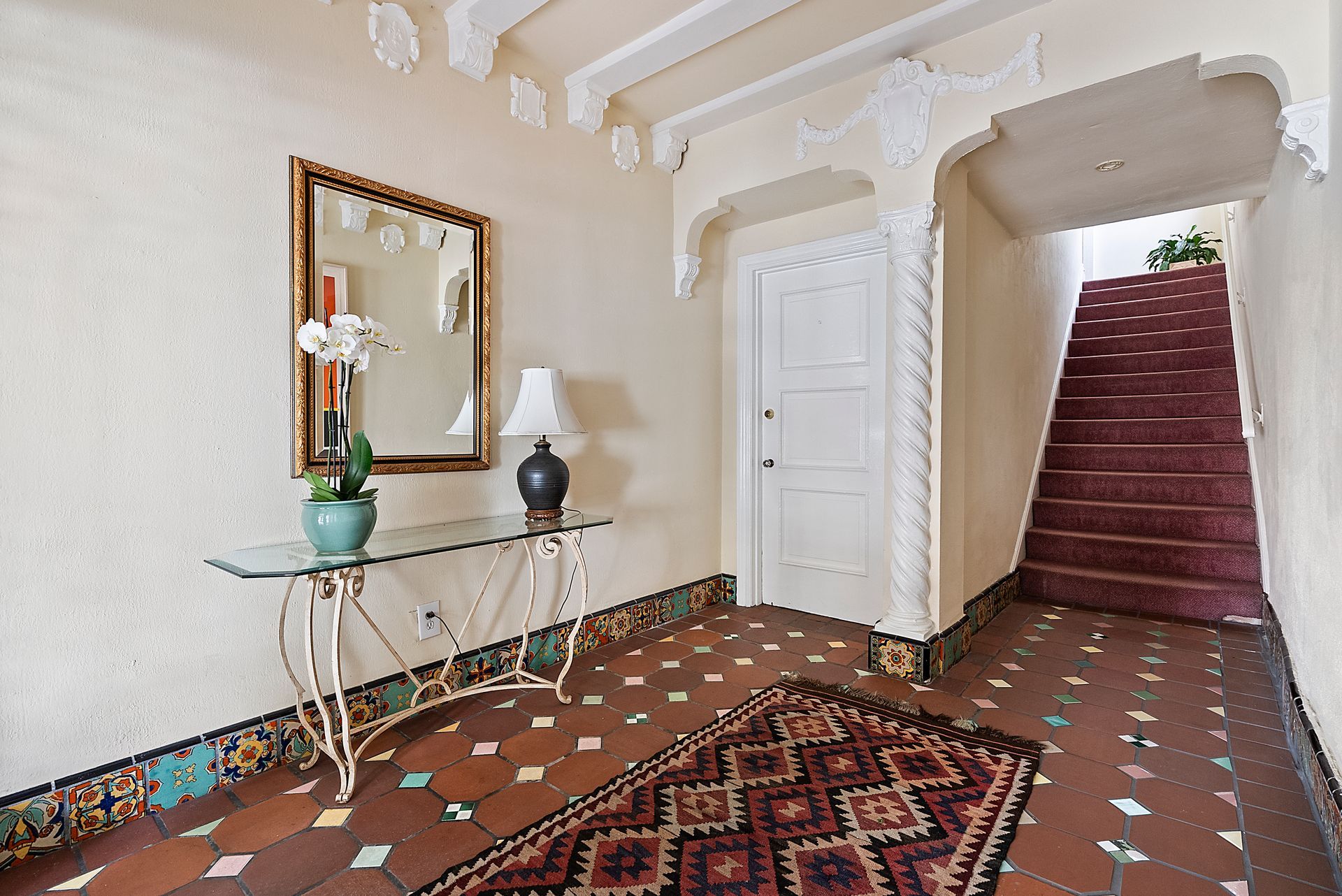 A hallway with stairs and a table with a lamp on it.