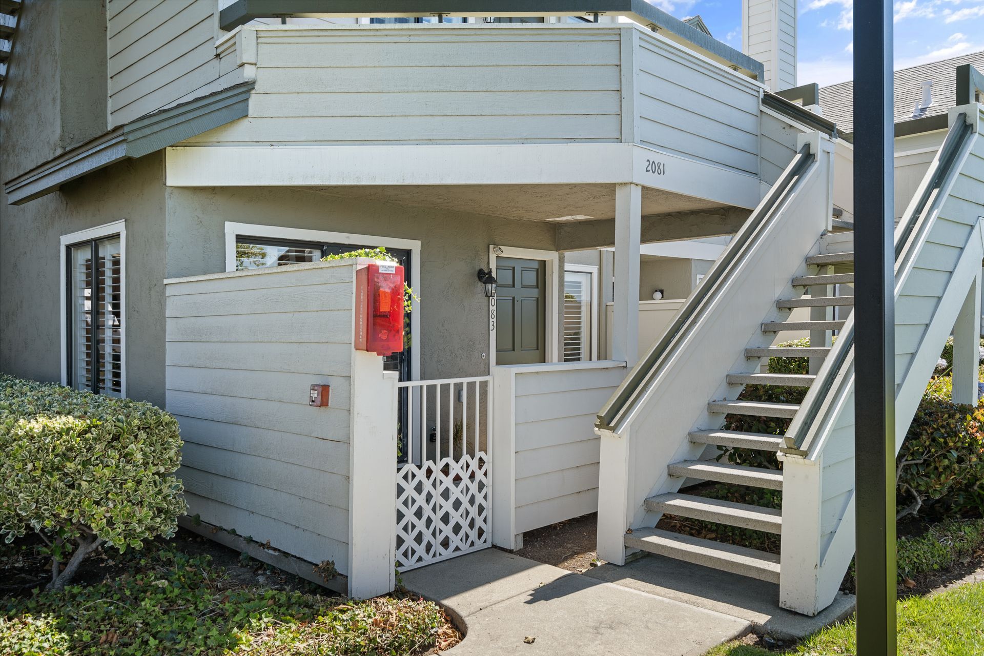 A white house with stairs leading up to the second floor.