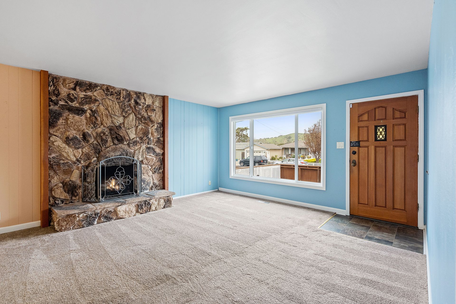 An empty living room with blue walls and a fireplace.