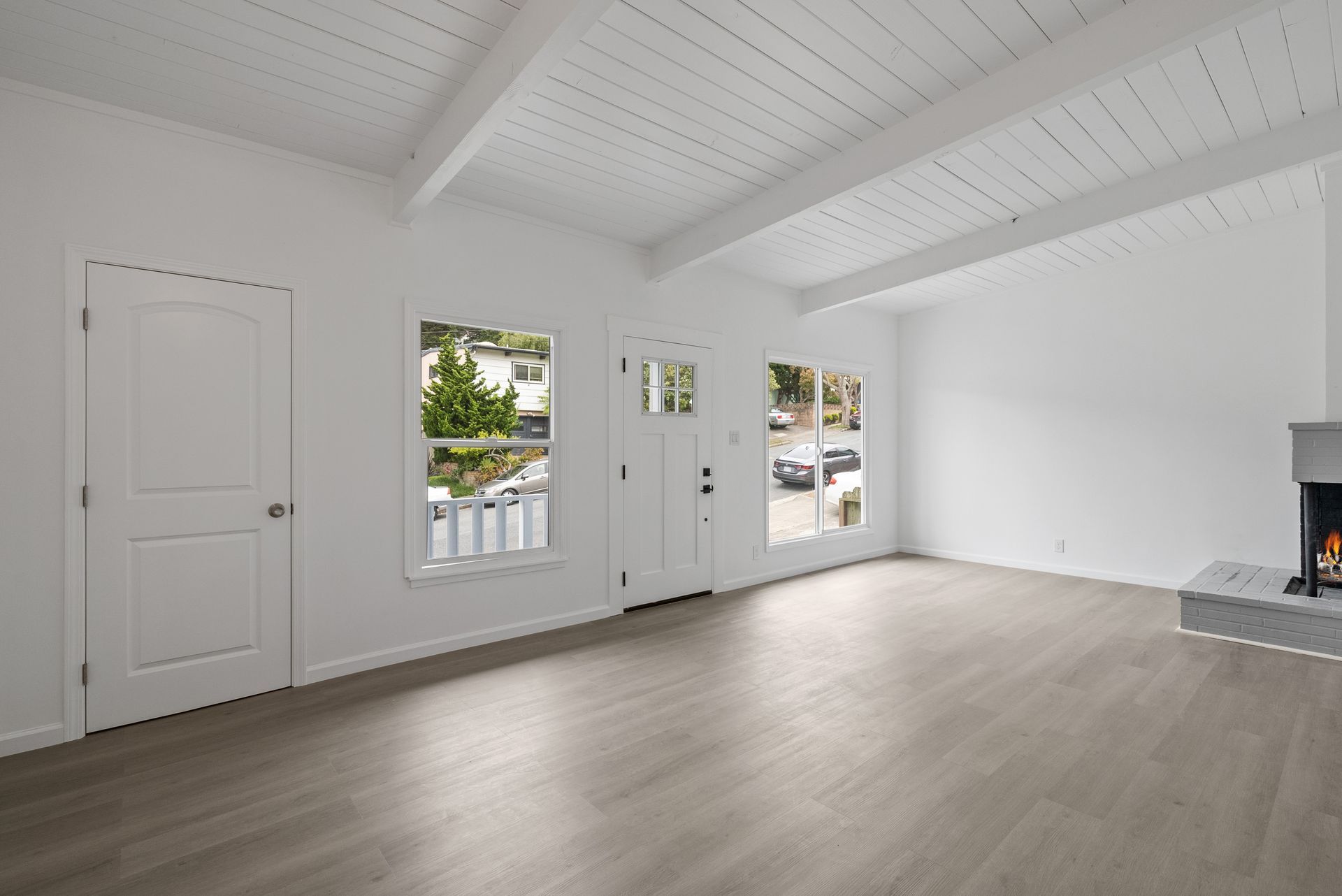 An empty living room with hardwood floors and a fireplace.
