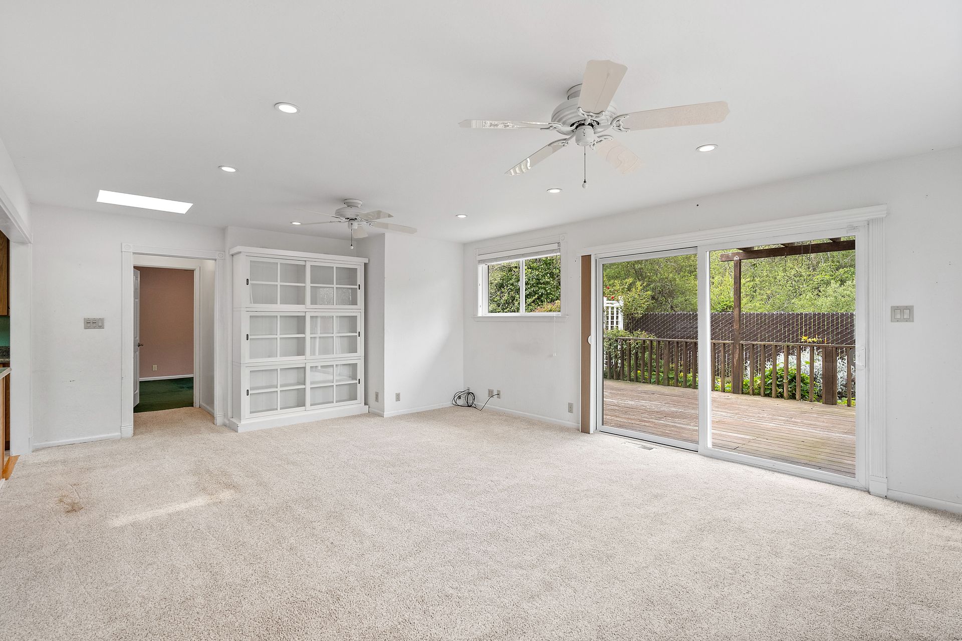An empty room with sliding glass doors and a ceiling fan.