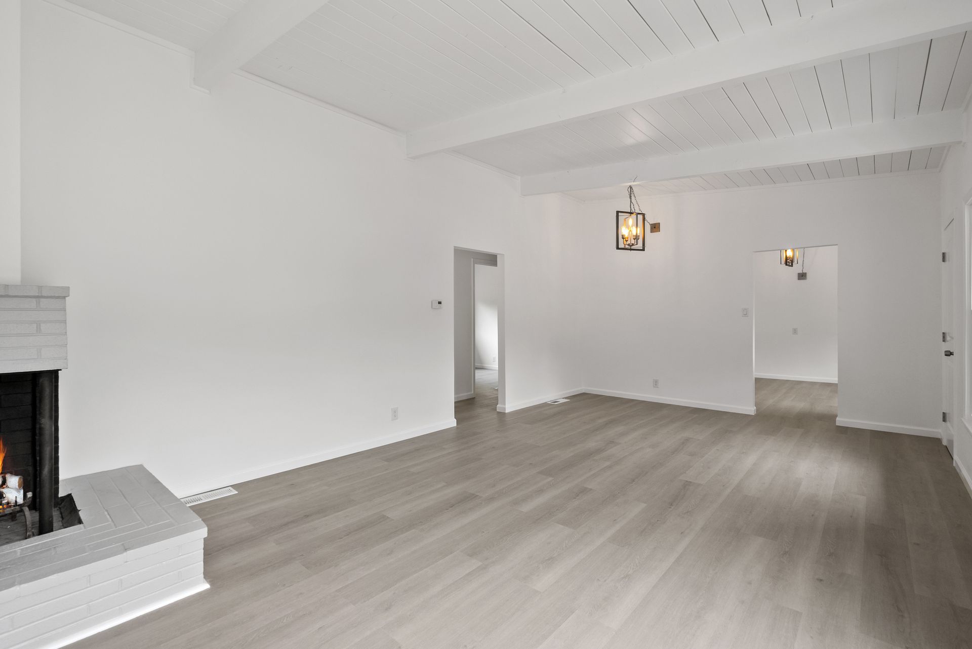An empty living room with a fireplace and hardwood floors.