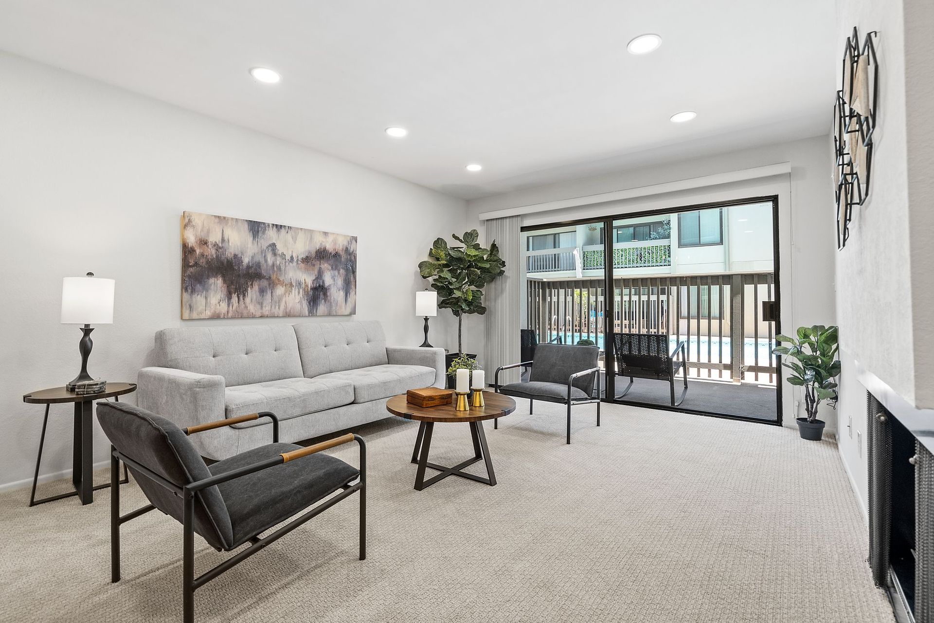 A living room with a couch , chairs , a table and a balcony.
