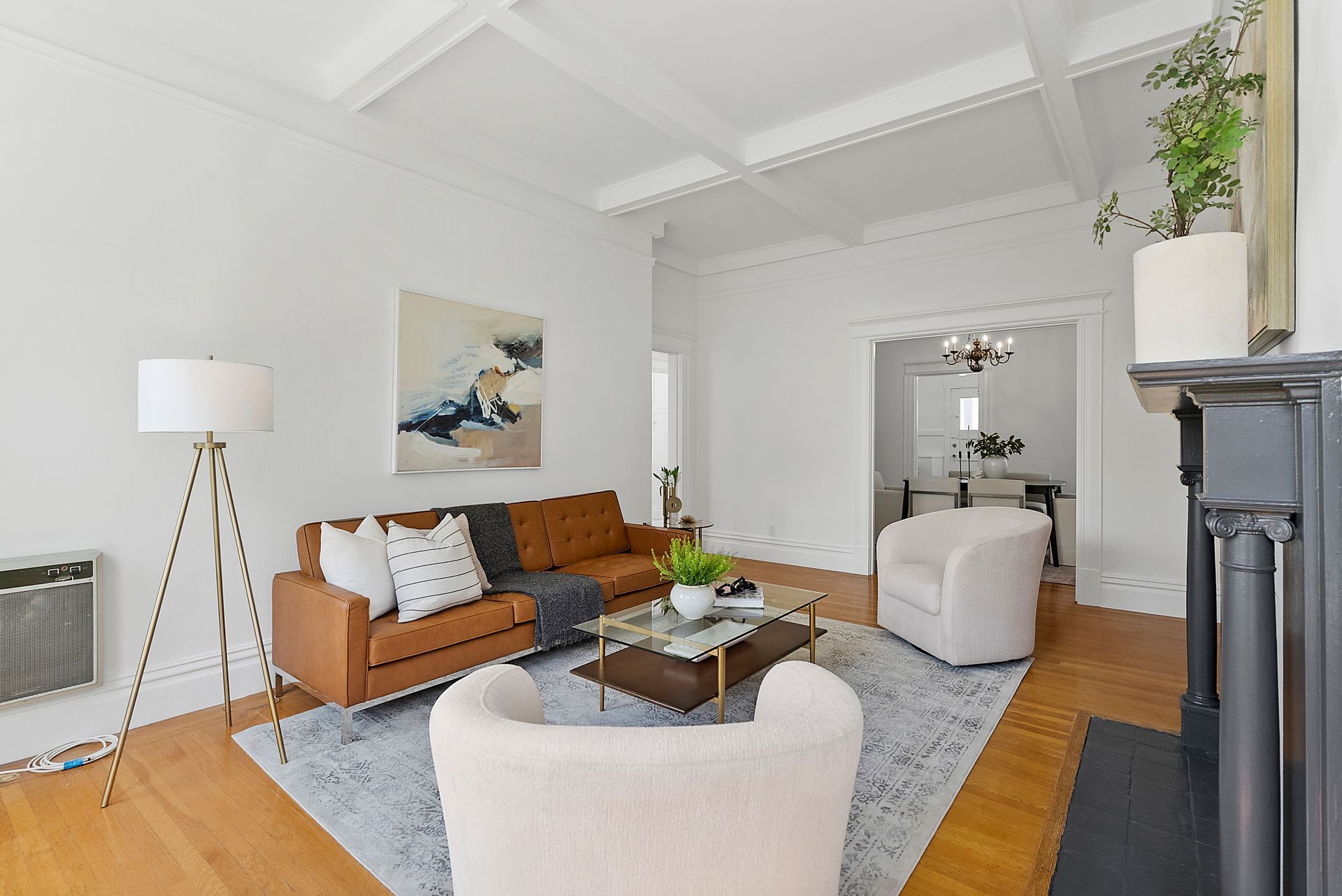A living room with a brown couch and white chairs.