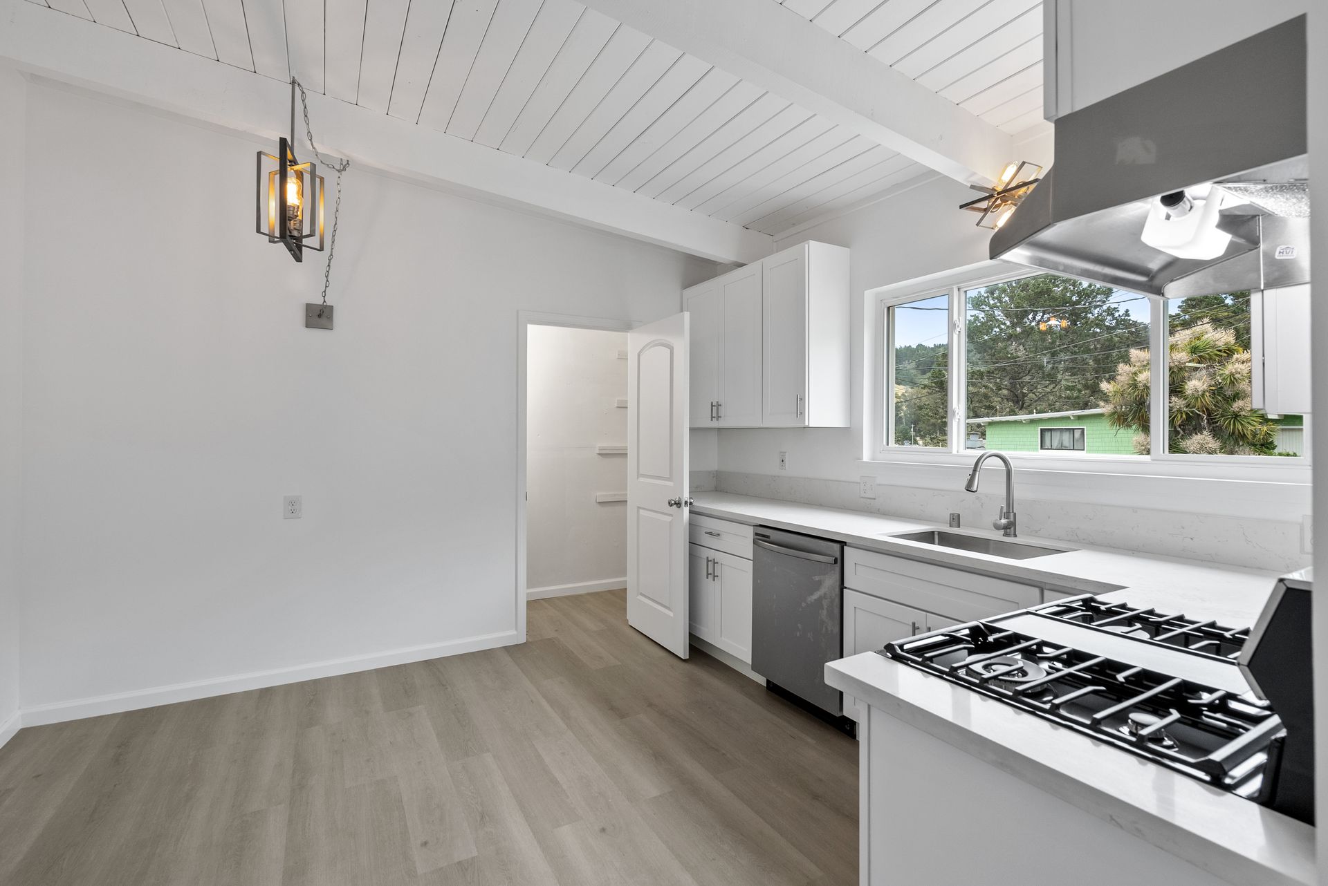 An empty kitchen with white cabinets and a stove top oven.