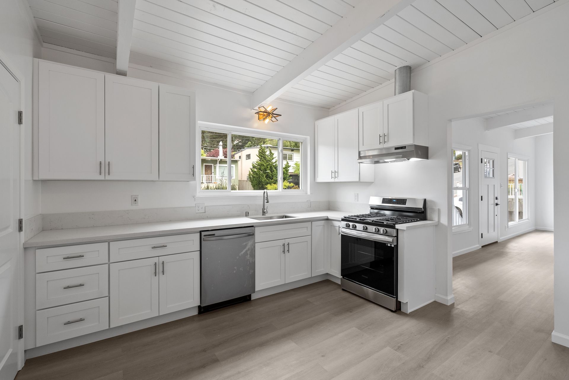 An empty kitchen with white cabinets and stainless steel appliances.