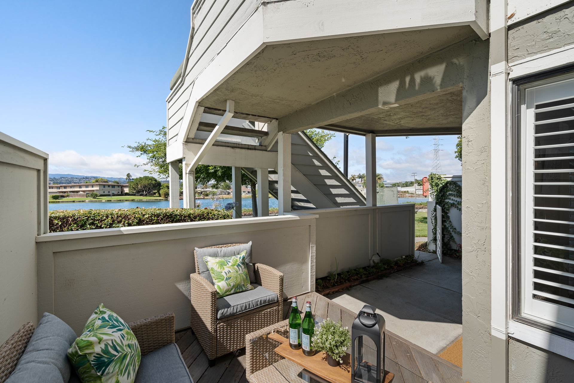 A balcony with a couch , chairs and a table with bottles of water on it.