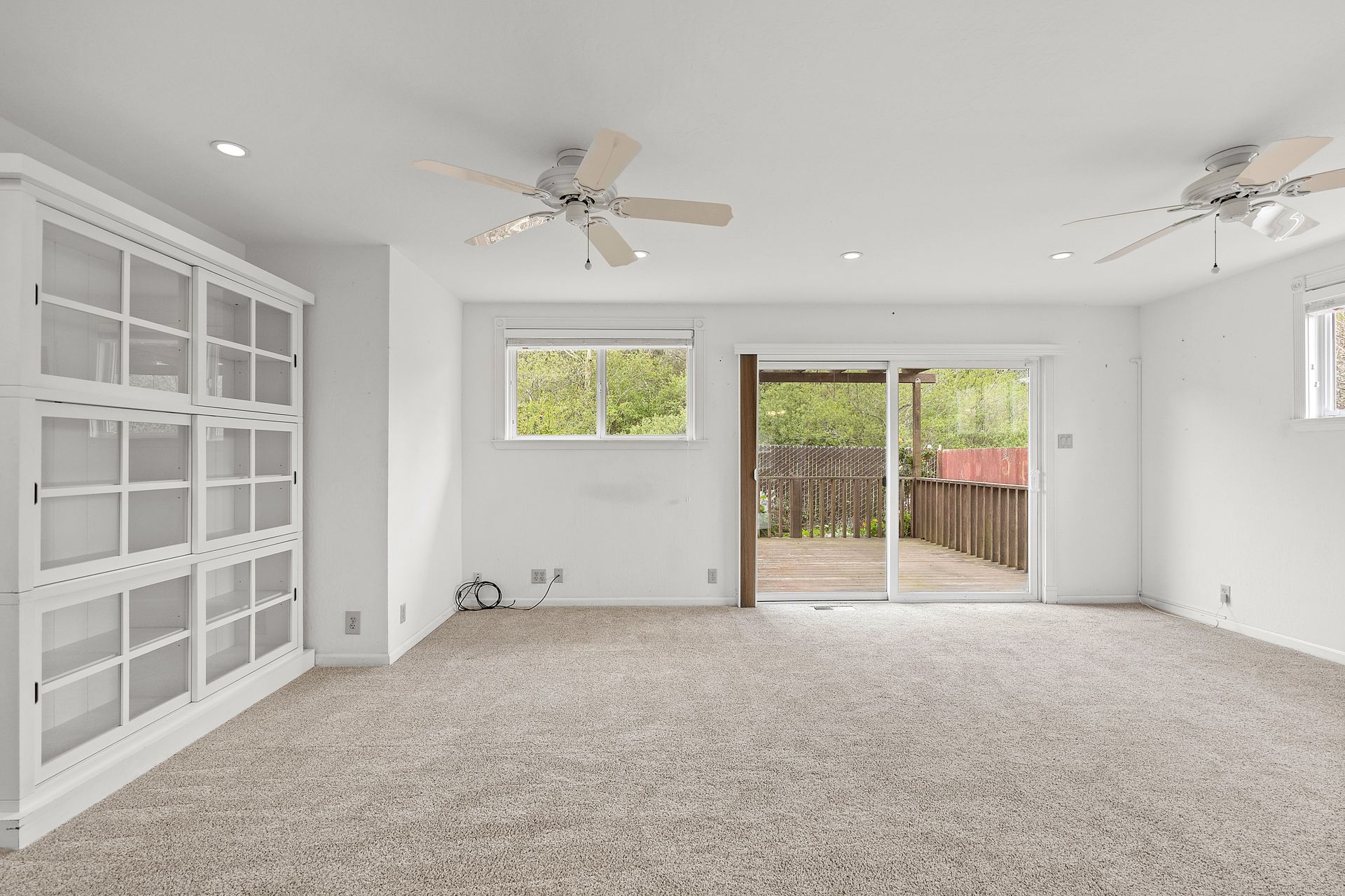 An empty room with a ceiling fan and a sliding glass door.