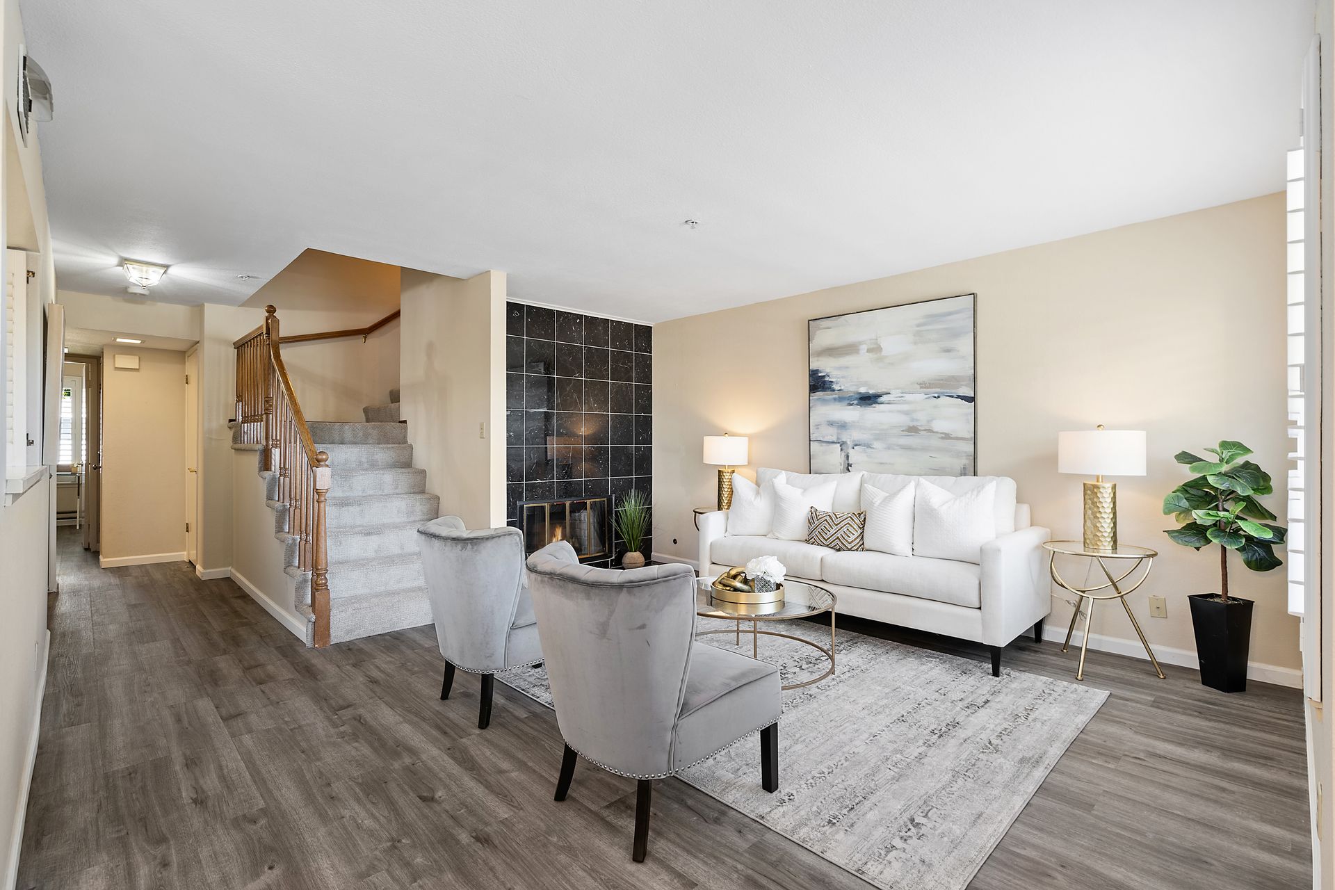 A living room with a couch and chairs and stairs