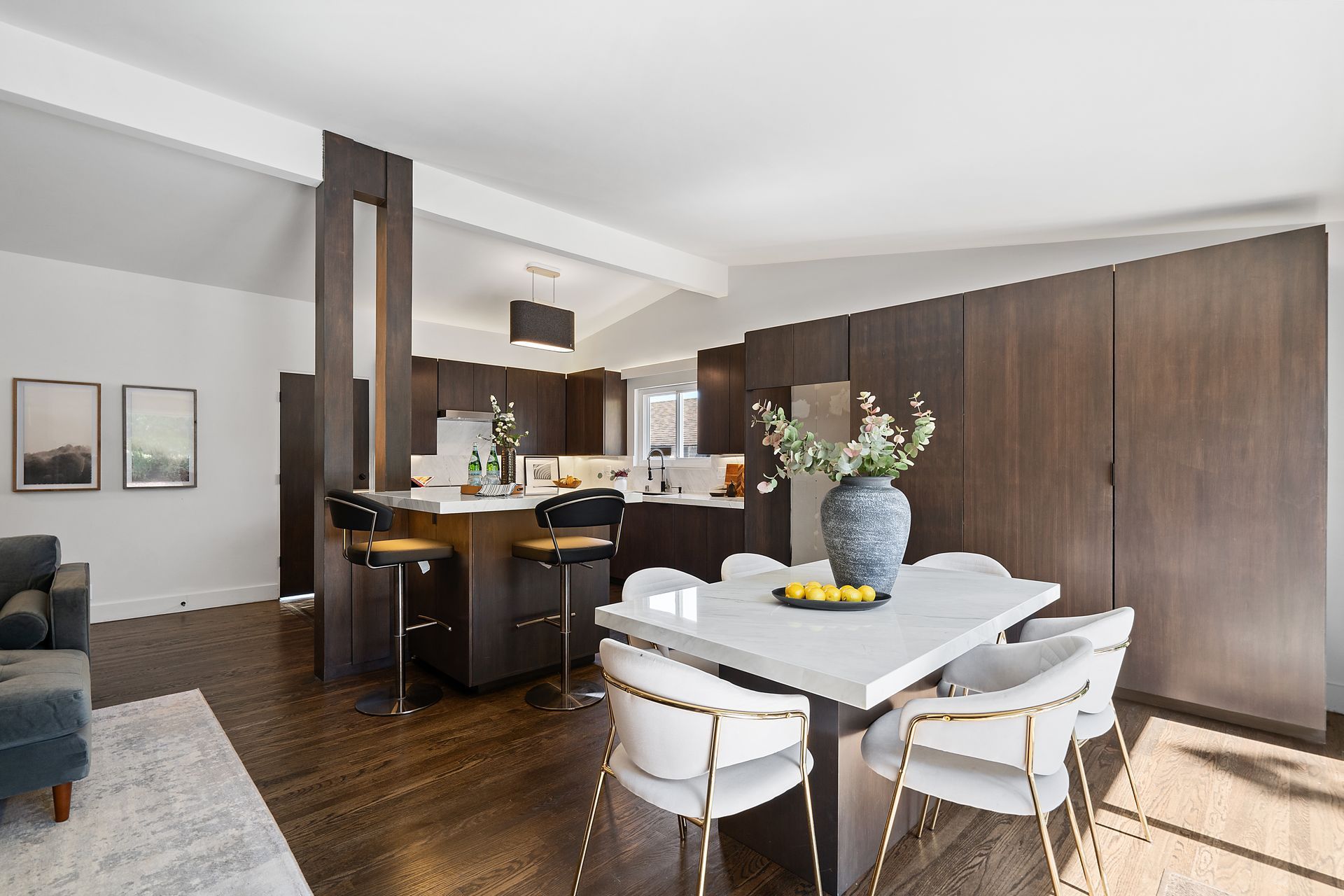 A dining room with a table and chairs and a vase of flowers on the table.