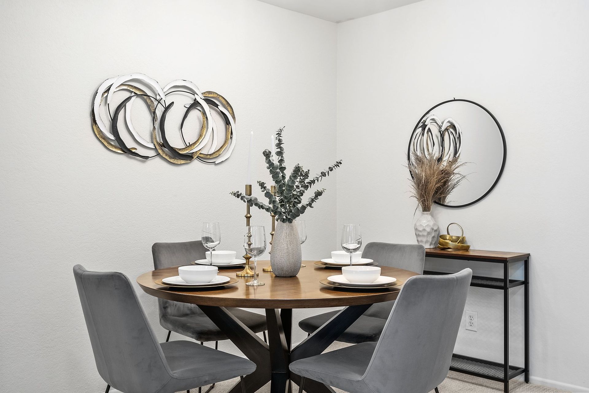 A room with a dining table and chairs and a vase of flowers on the table.
