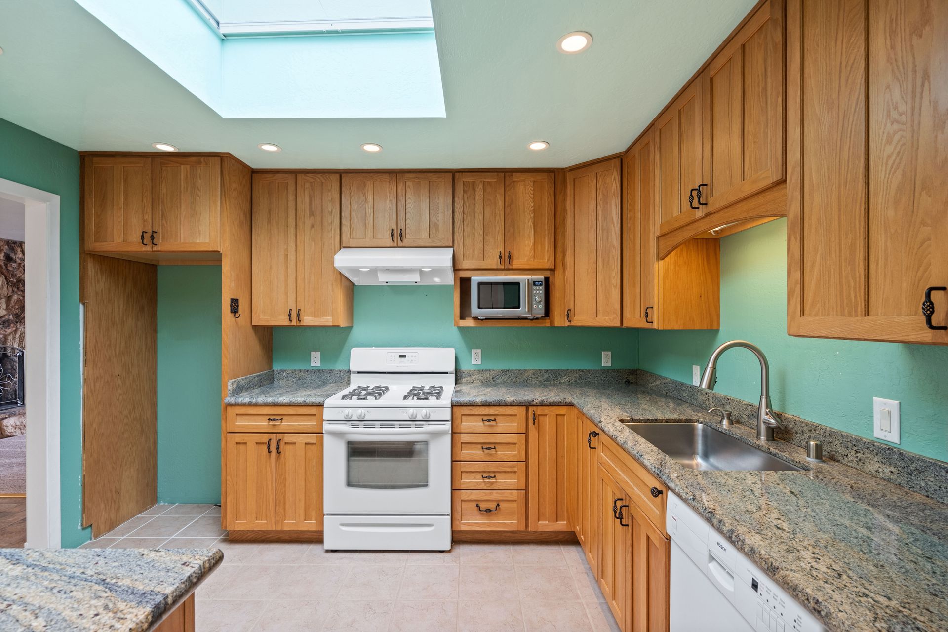 A kitchen with wooden cabinets and a skylight above the stove