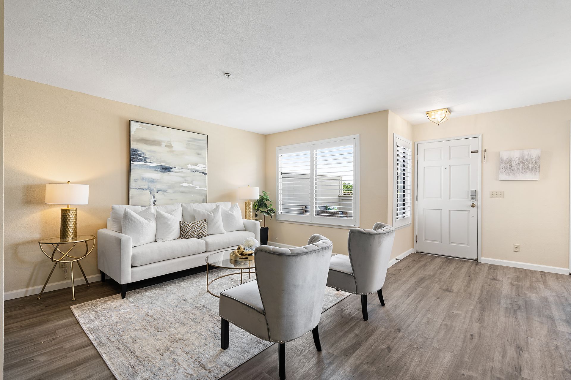 A living room with a white couch and two chairs