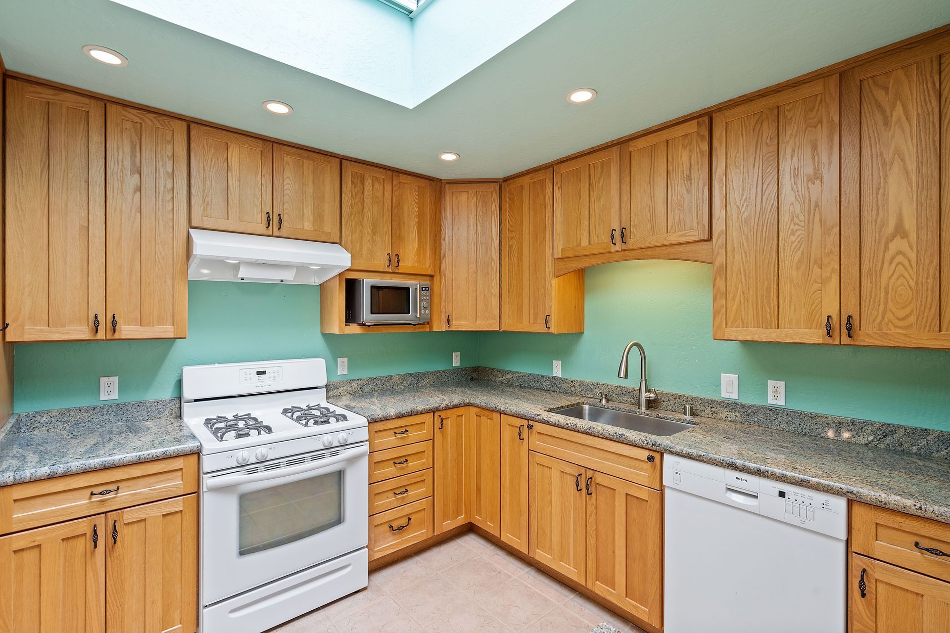 A kitchen with wooden cabinets and a white stove.