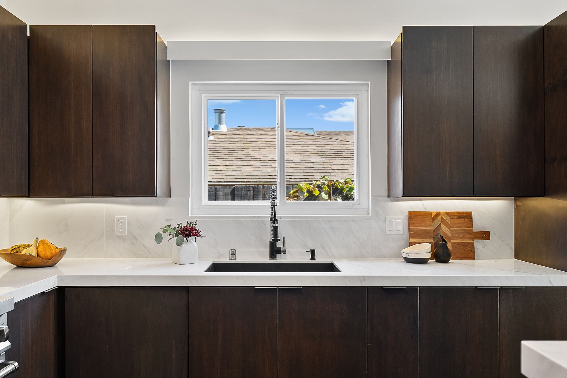 A kitchen with a sink and a window with a view of the roof.