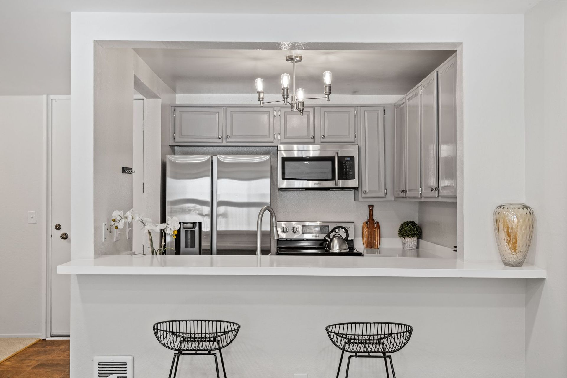 A kitchen with white cabinets , stainless steel appliances , a refrigerator and a microwave.
