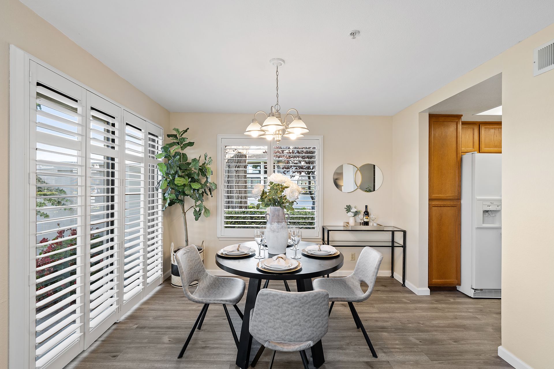 A dining room with a table and chairs and shutters on the windows