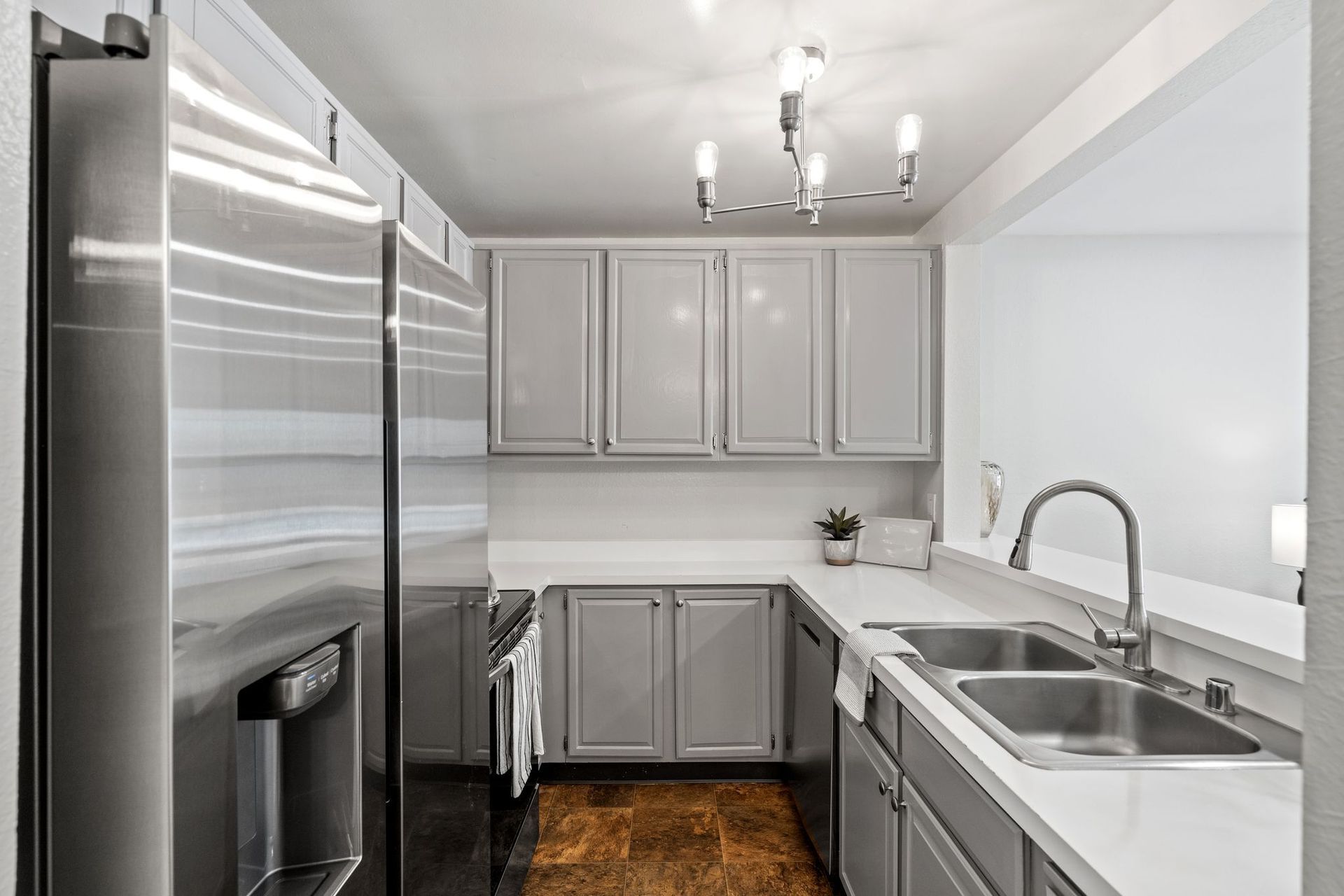 A kitchen with stainless steel appliances and gray cabinets.