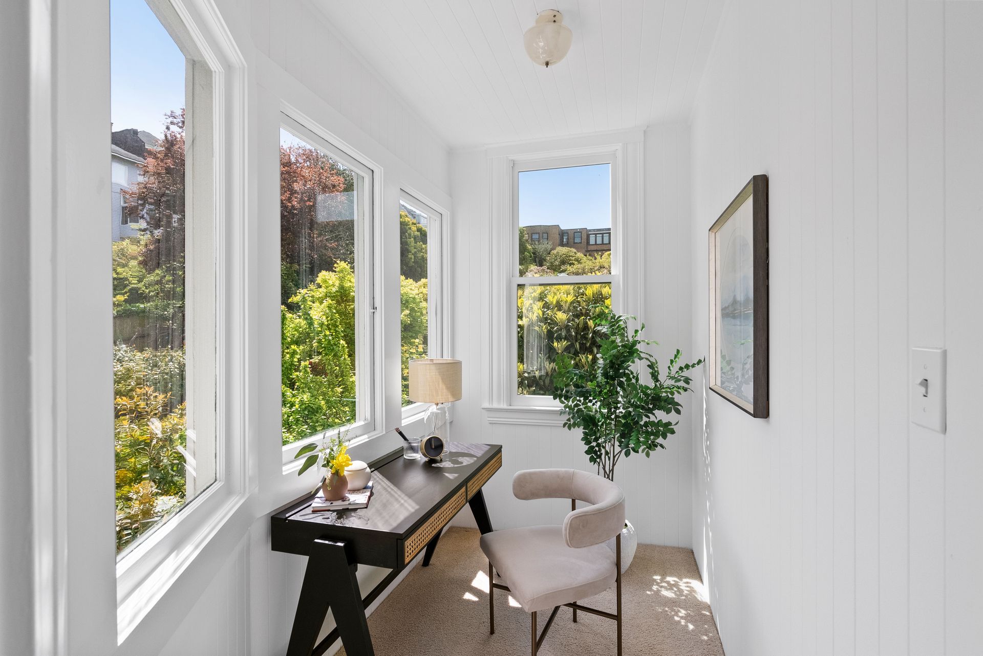 A home office with a desk and chair and lots of windows.