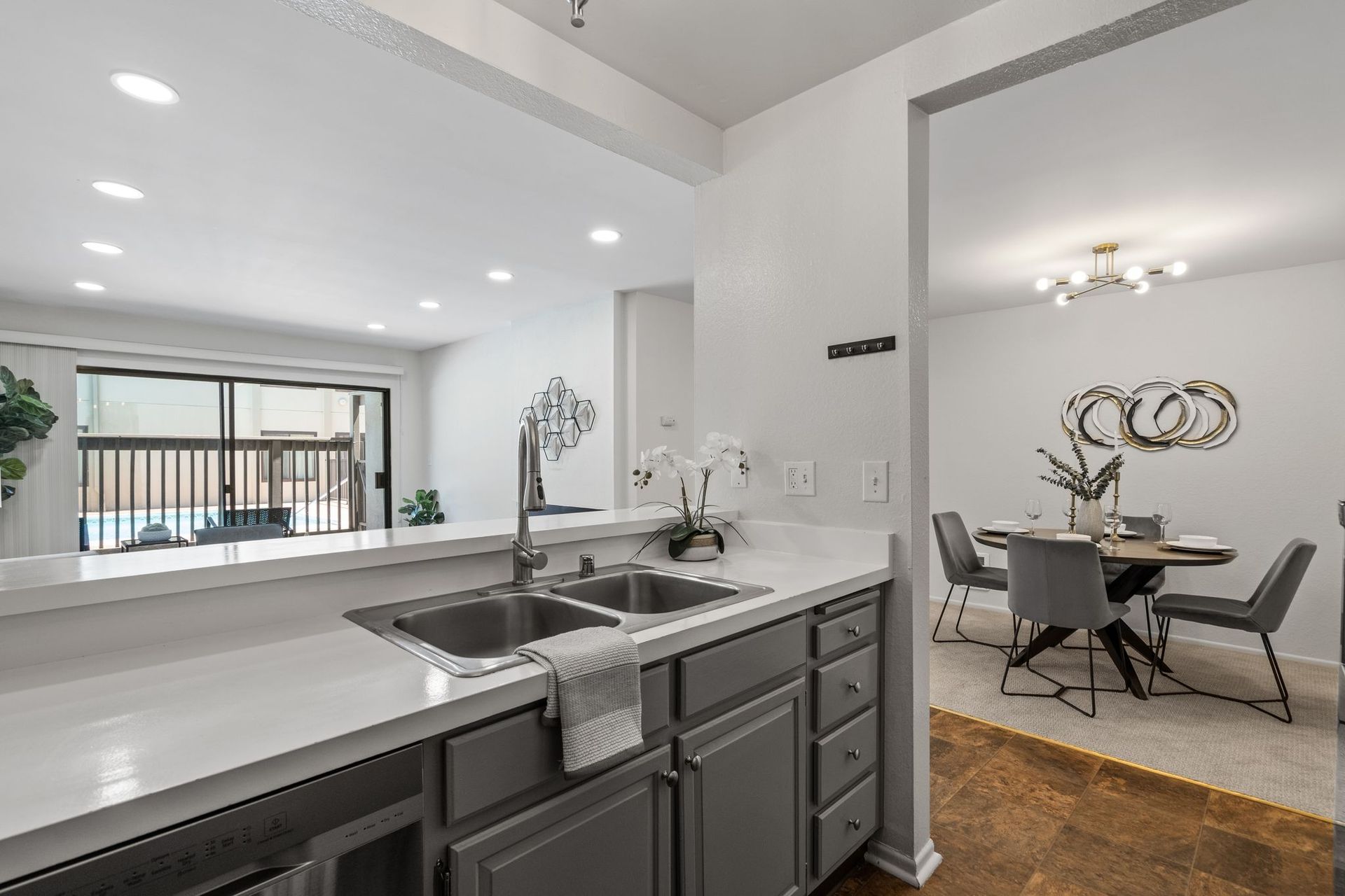 A kitchen with double sinks and a dining room in the background.