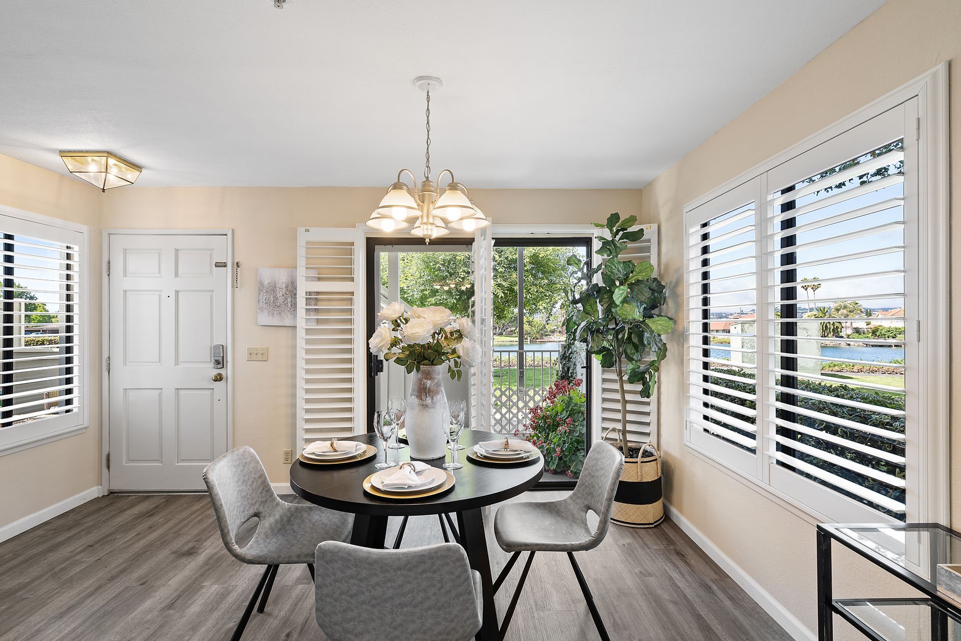 A dining room with a table and chairs and shutters on the windows.