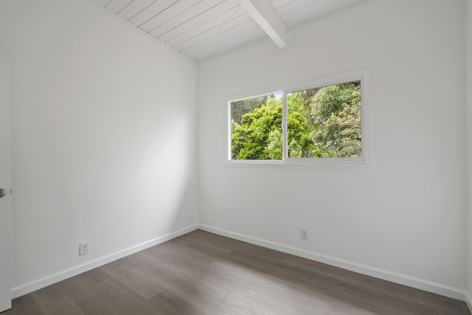 An empty room with windows and a wooden floor.