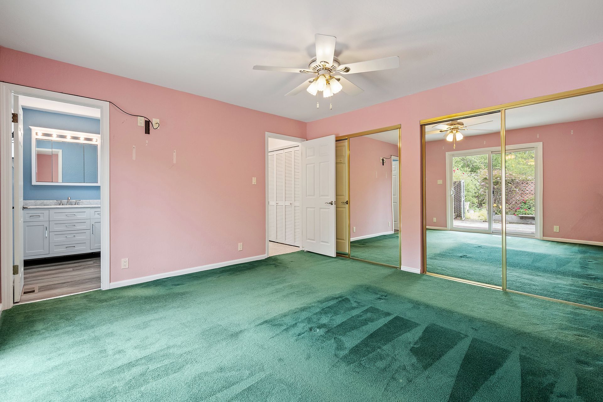 An empty room with pink walls and green carpet.