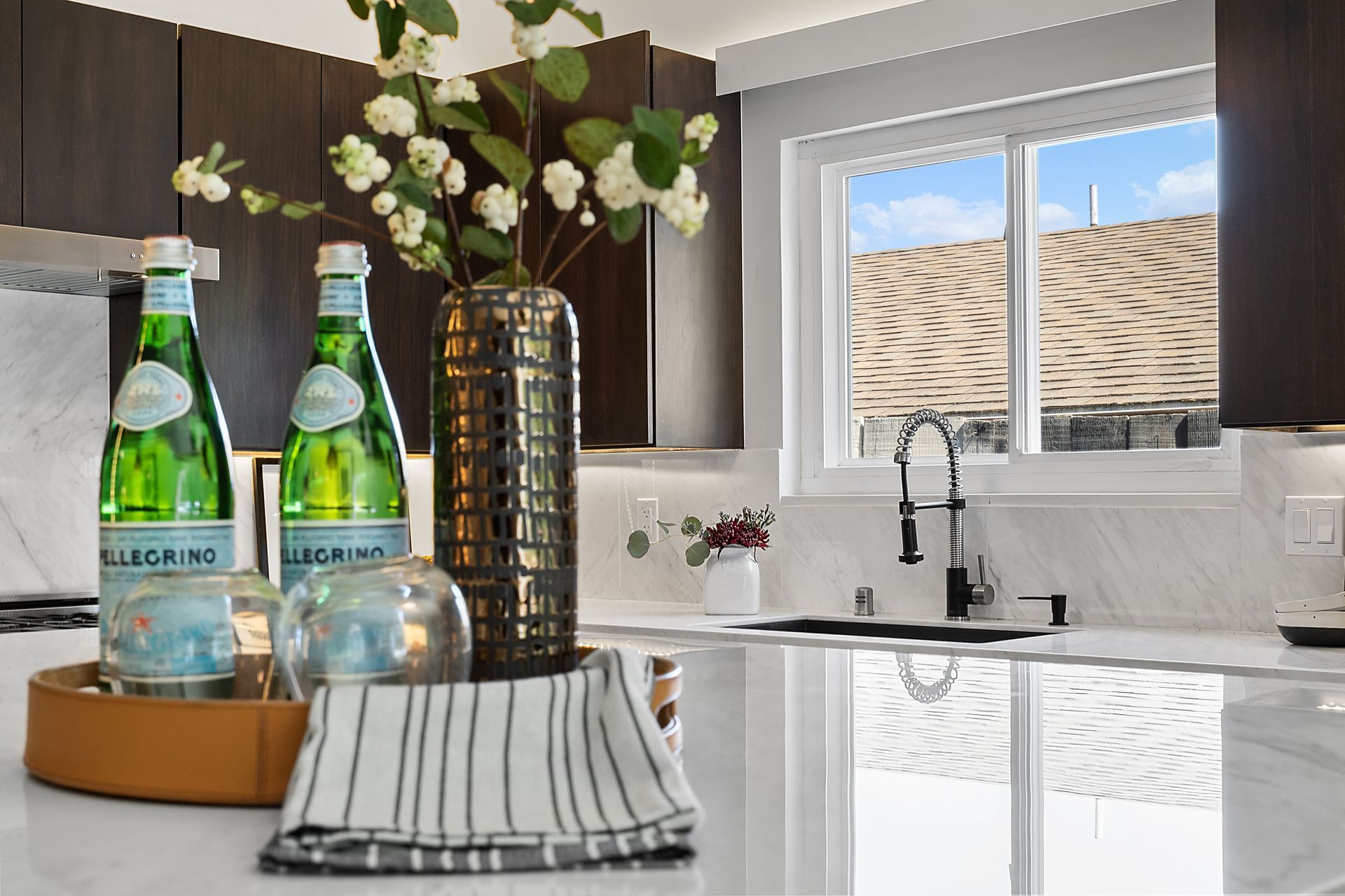 A kitchen with two bottles of water and a vase of flowers on the counter.