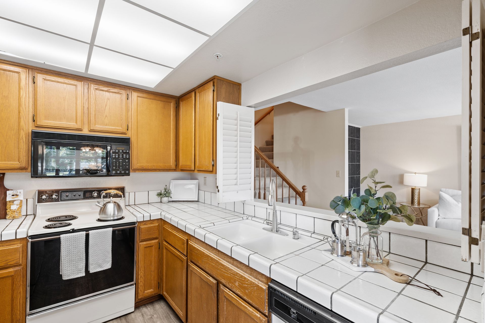 A kitchen with wooden cabinets and white tile counter tops