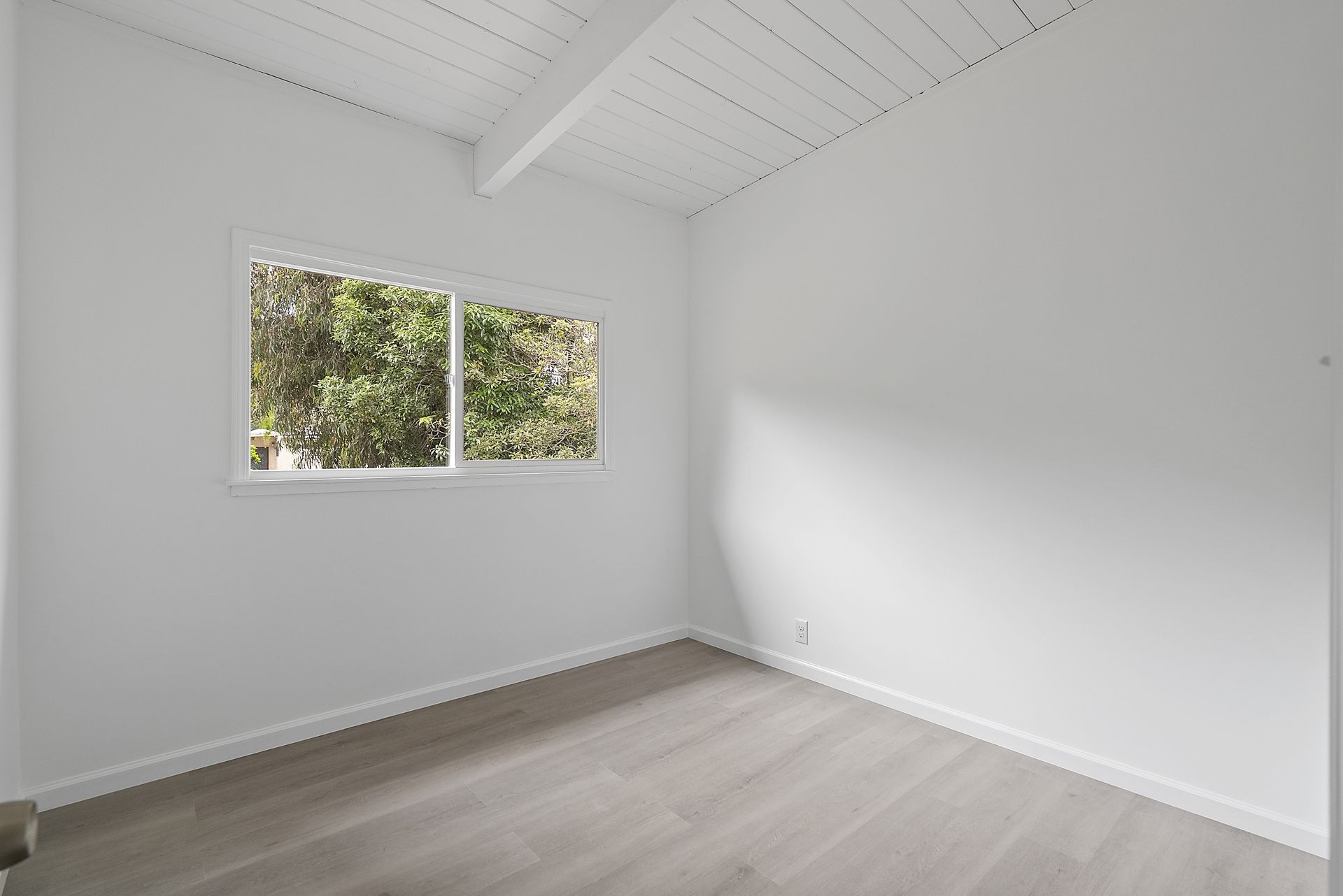 An empty room with windows and a wooden floor.