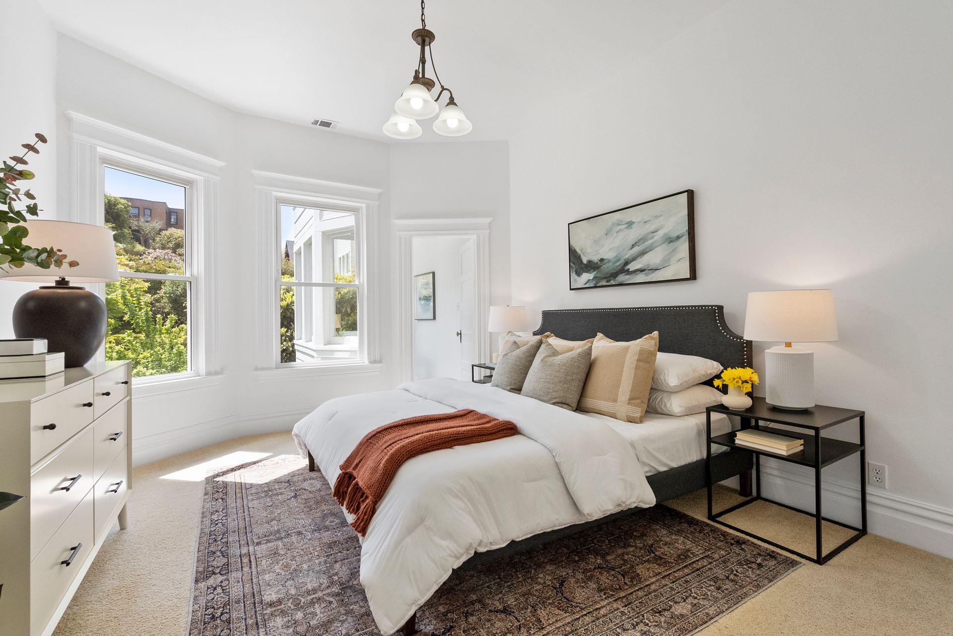 A bedroom with a bed, nightstands and a rug.
