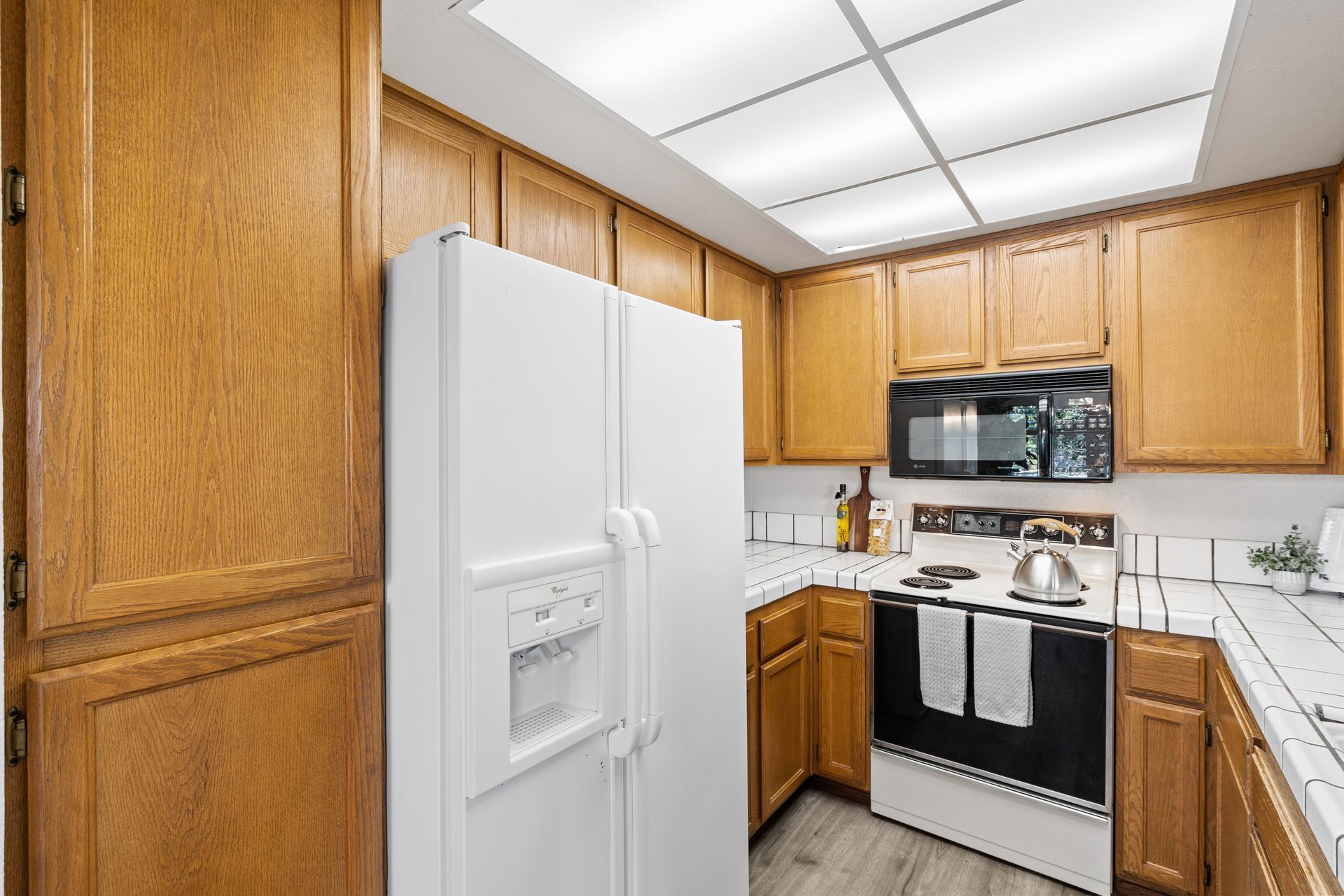 A kitchen with wooden cabinets , a white refrigerator , a stove , and a microwave.